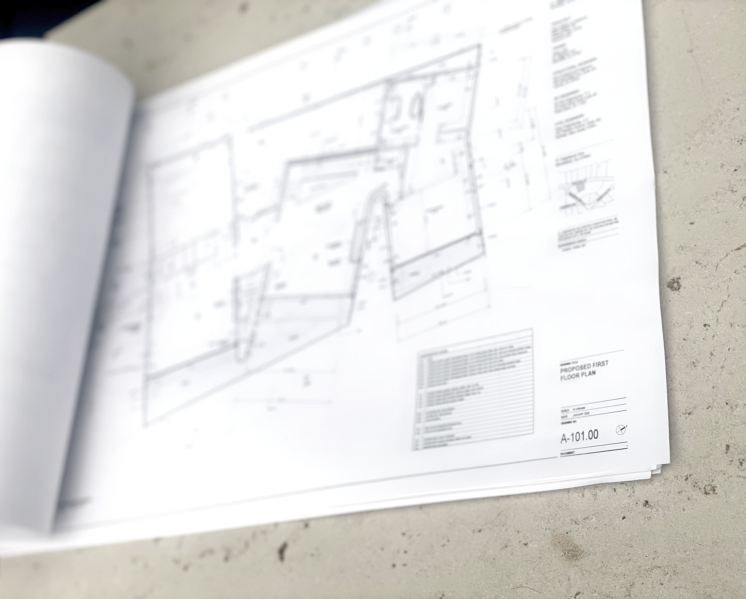 Architectural blueprint of a proposed first floor plan on a construction table.
