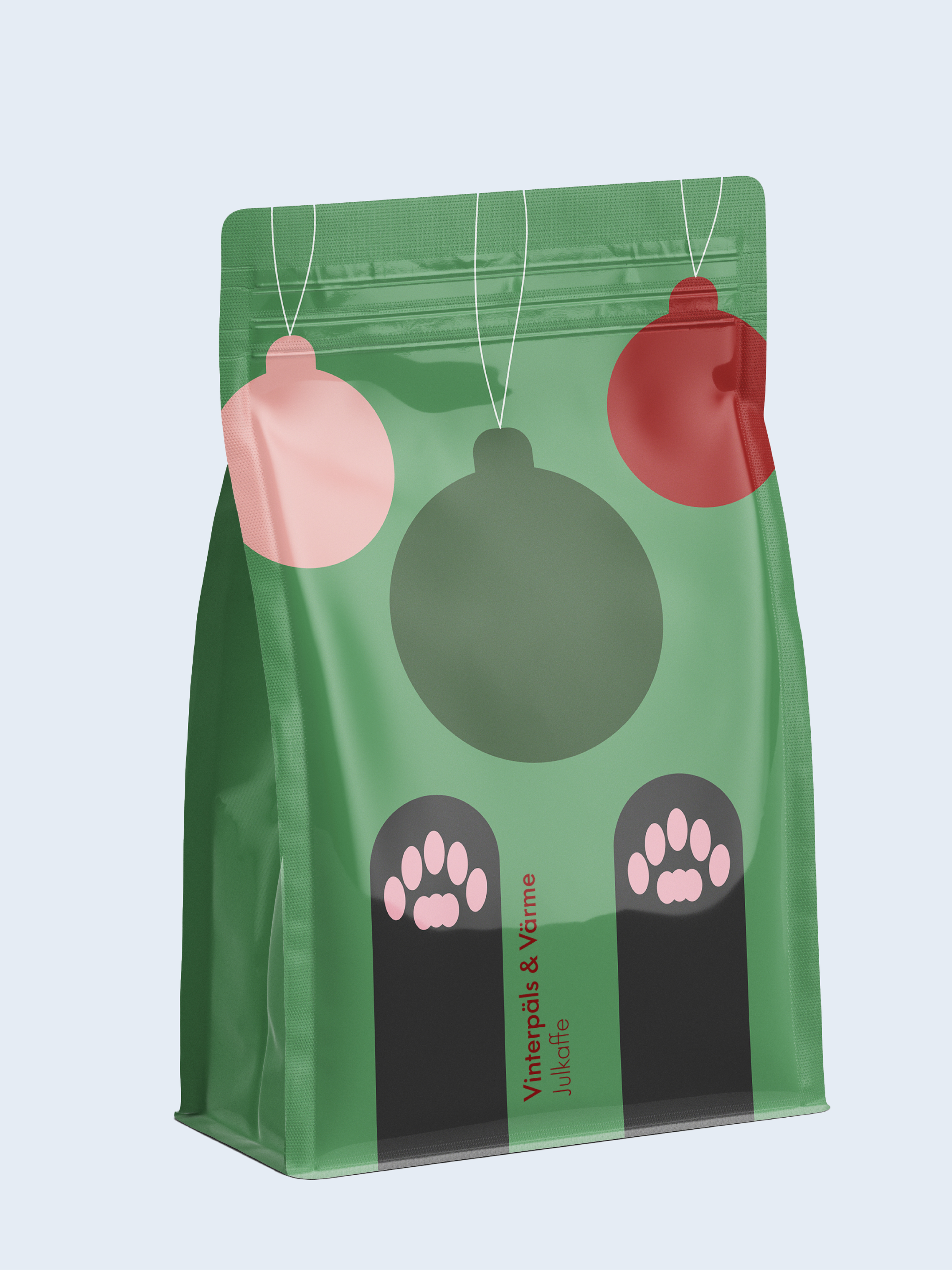En grön papperspåse med julgranskulor och tassavtryck, texten 'Vinterpäls & Värme Julkaffe' på.