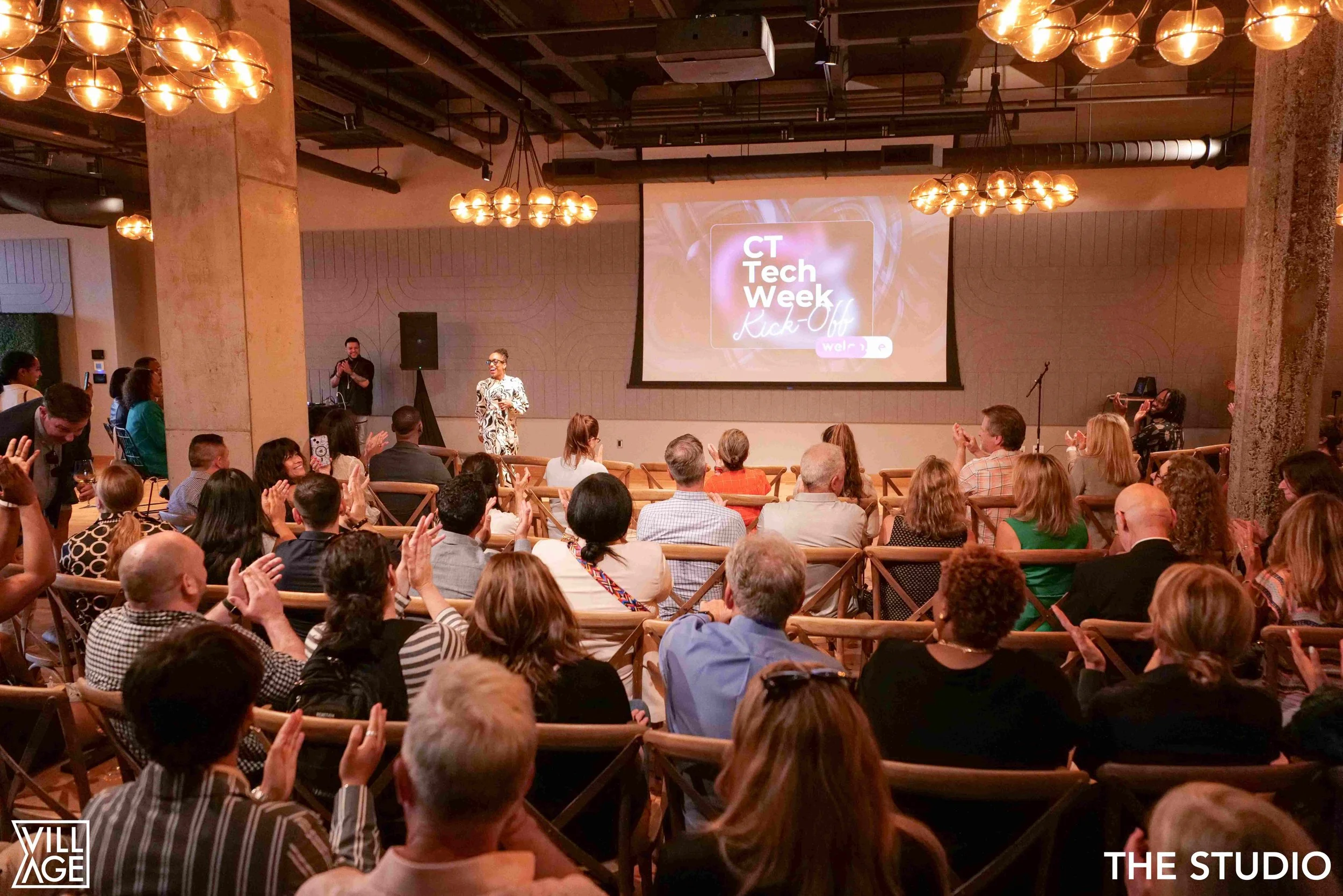 Audience attending a presentation at CT Tech Week Kick-Off event in a modern conference room with a large screen displaying the event name