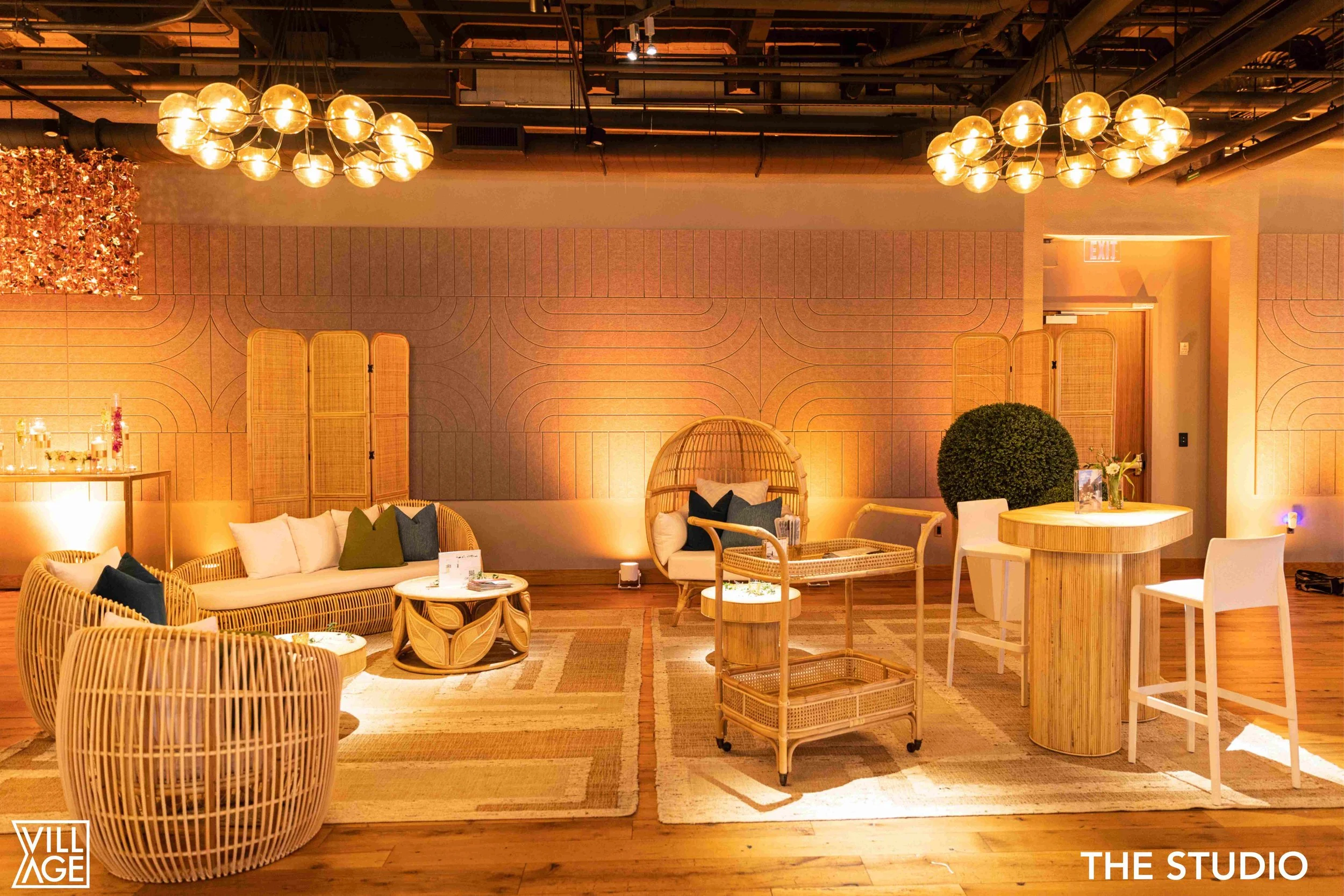 Empty stylish lounge with wicker and wooden furniture, plush pillows, a woven hanging chair, a round wooden table, a plants, and soft warm lighting in a modern interior
