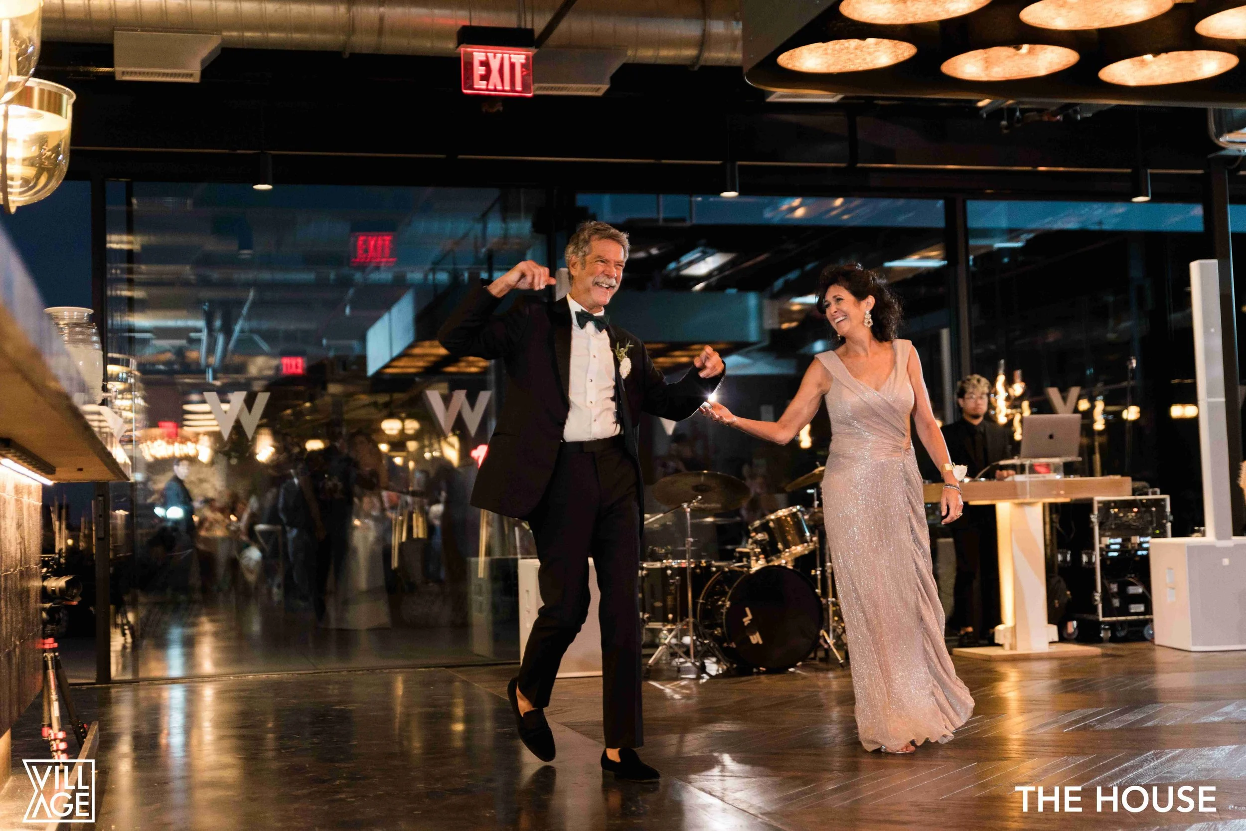 A man and woman dancing at a formal event with a live band performing in the background at night.