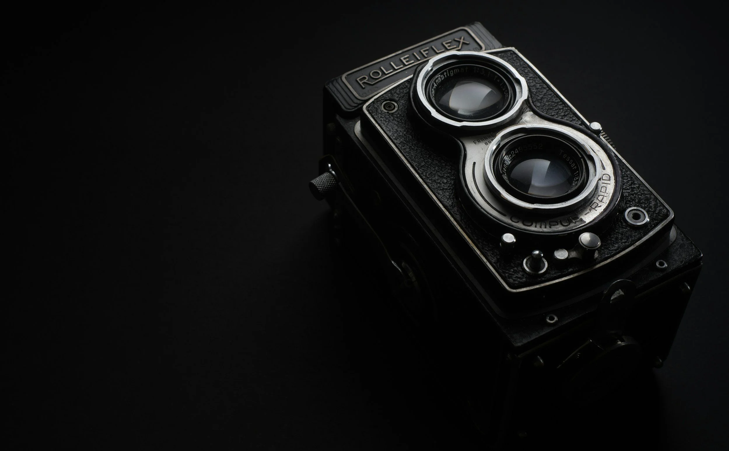 A vintage Rolleiflex twin-lens reflex camera against a black background.