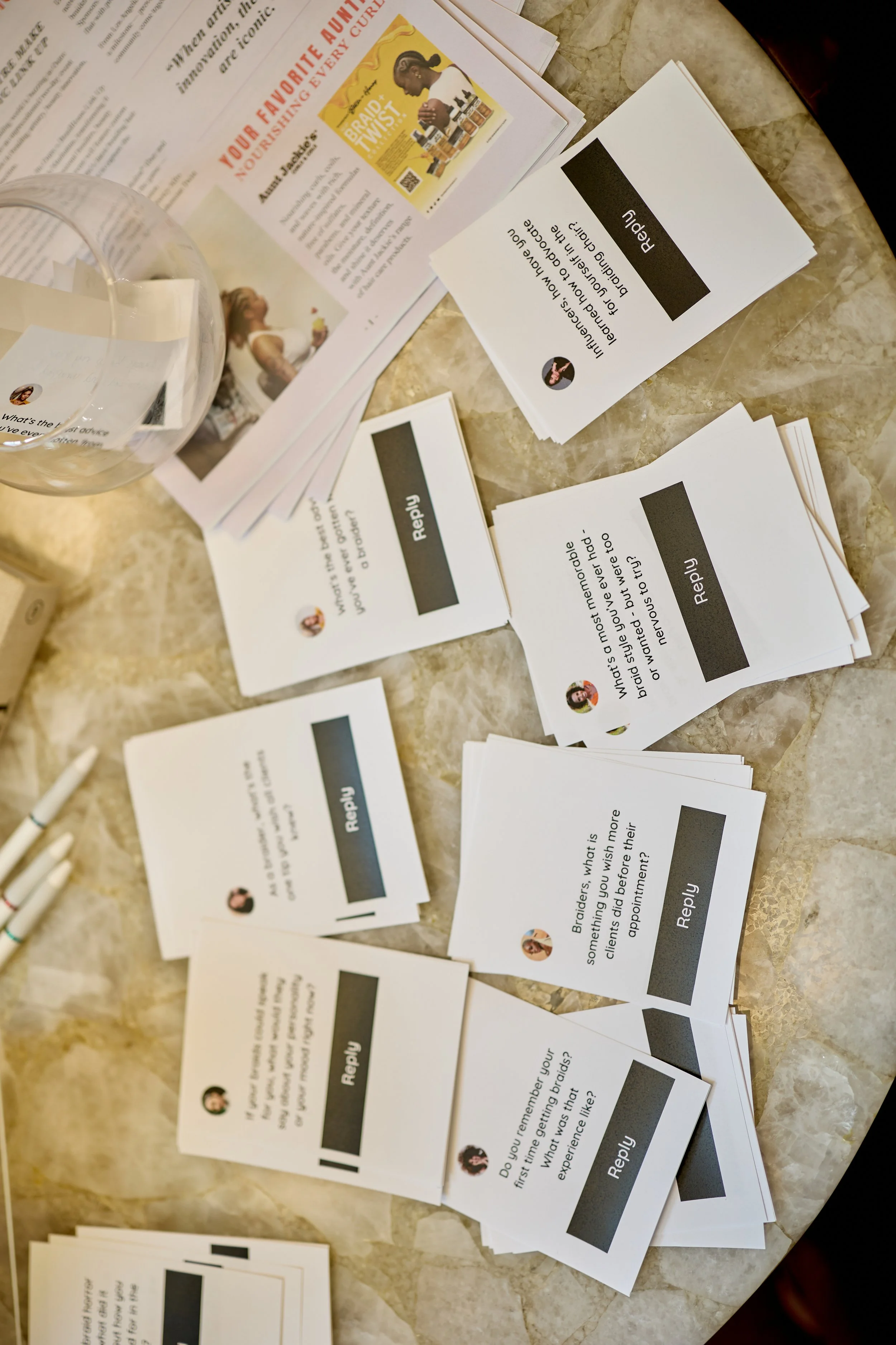 Various cards with questions and reply options are spread out on a marble table, along with a glass of water and some magazines or pamphlets.