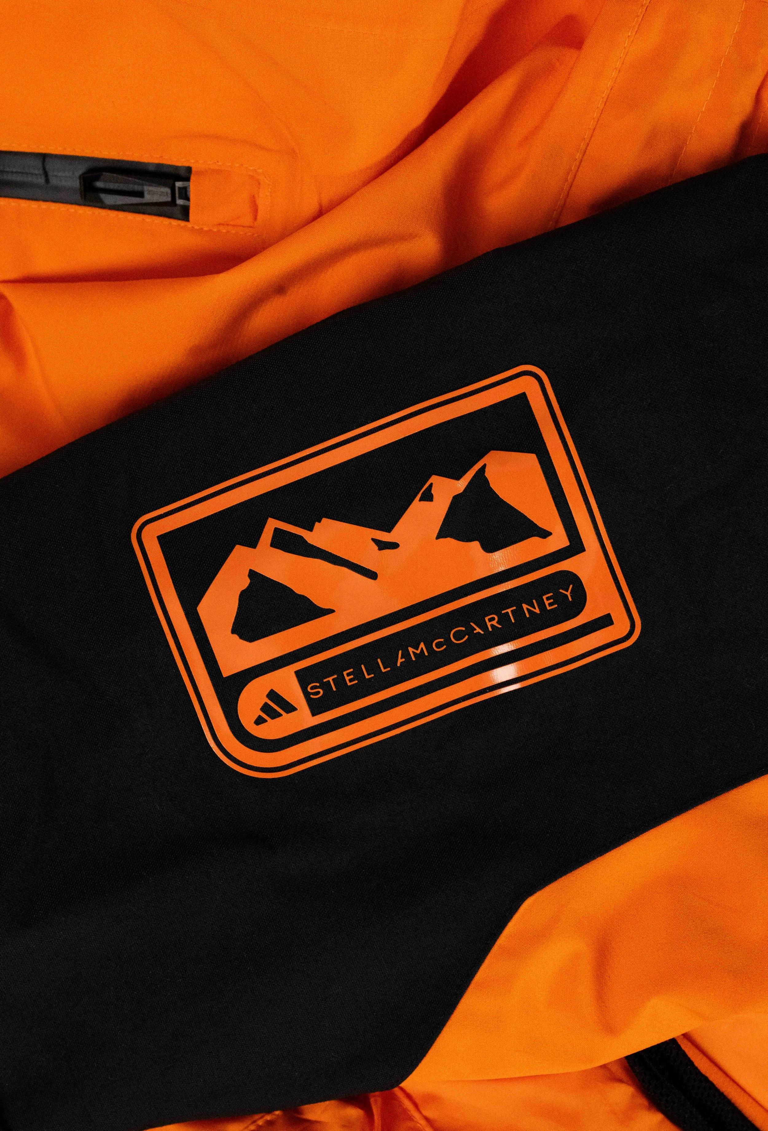 Close-up of a black and orange gear bag with the Stella McCartney x Adidas logo featuring mountain peaks.