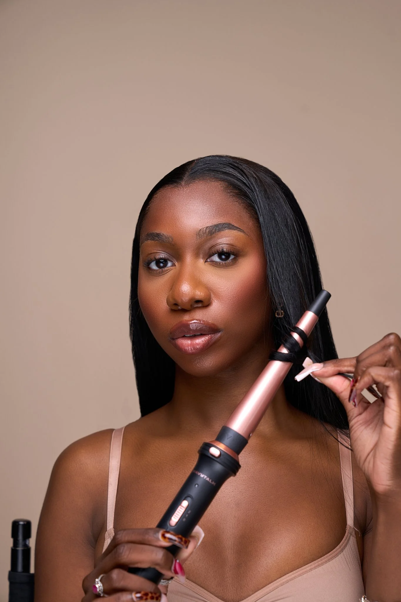 A woman with long black hair holding a curling iron.