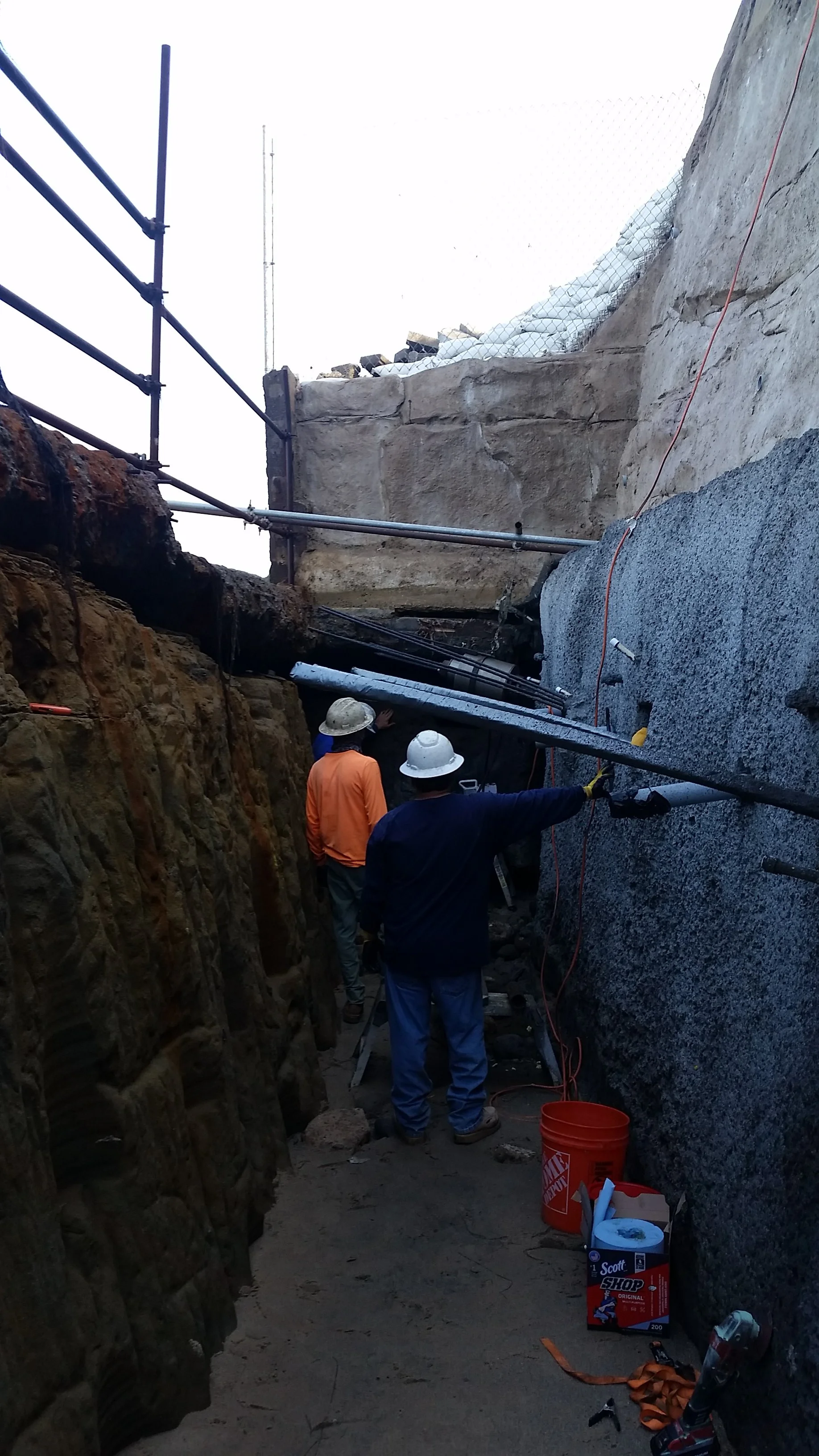 Two workers conducting tieback testing during seawall construction