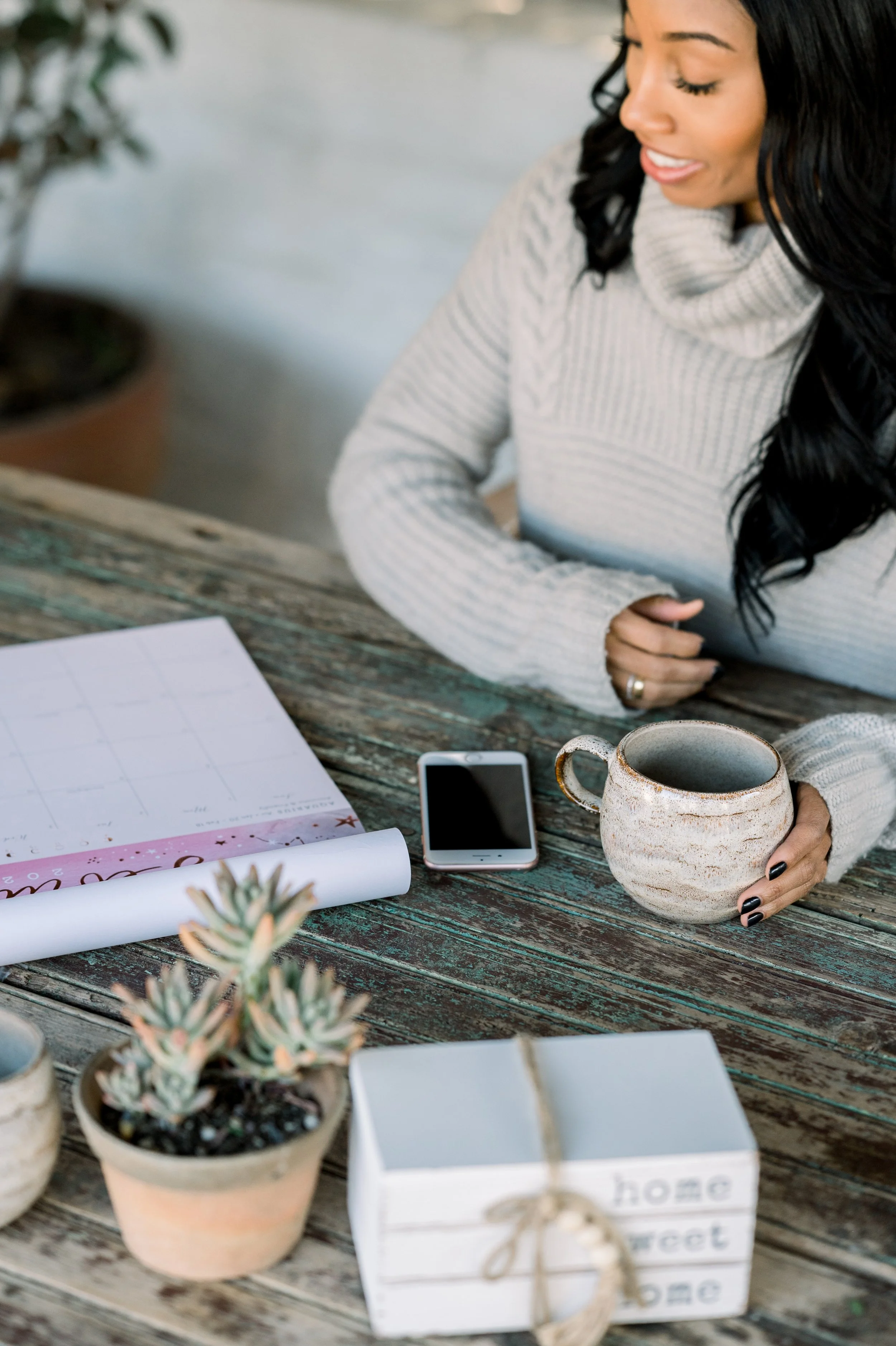ISS-Home-Office with woman looking at planner, phone and coffee cup on desk, showing calm clarity in her work.