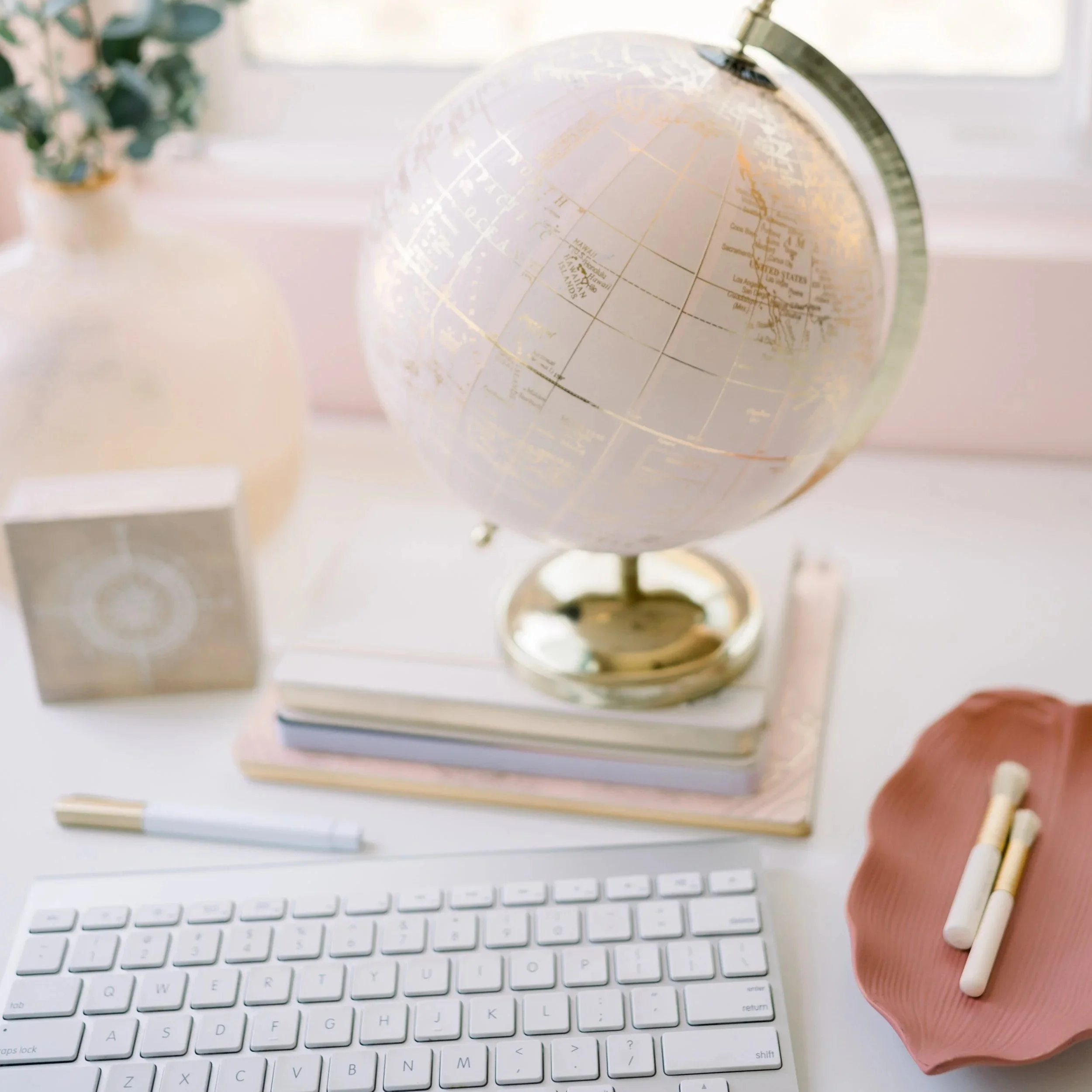 Workspace with Blush Globe, keyboard, pen, and flowers, representing intuitive content creation.