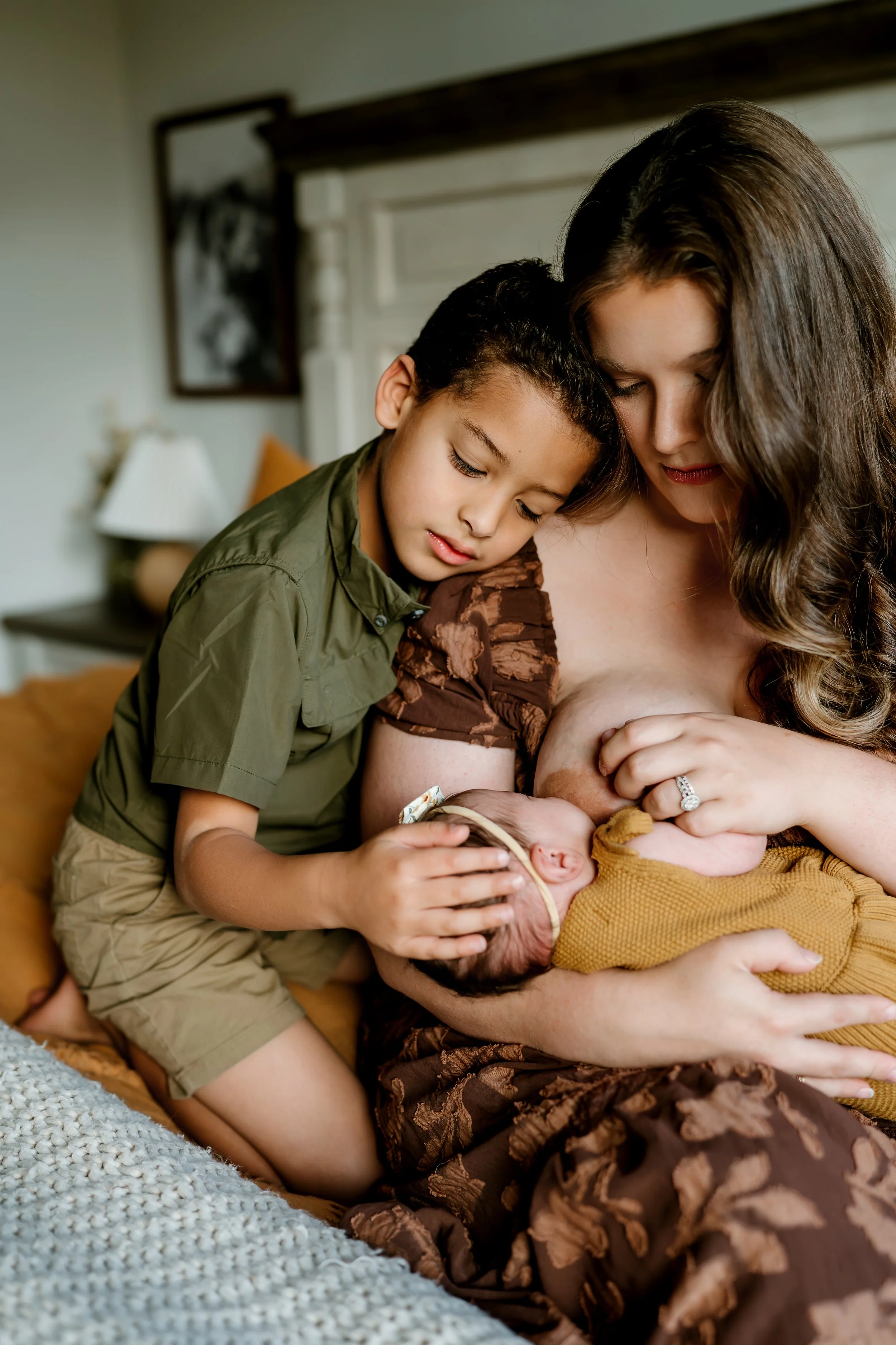 Mother and young son holding their newborn baby during a cozy family photography session in The Woodlands, TX