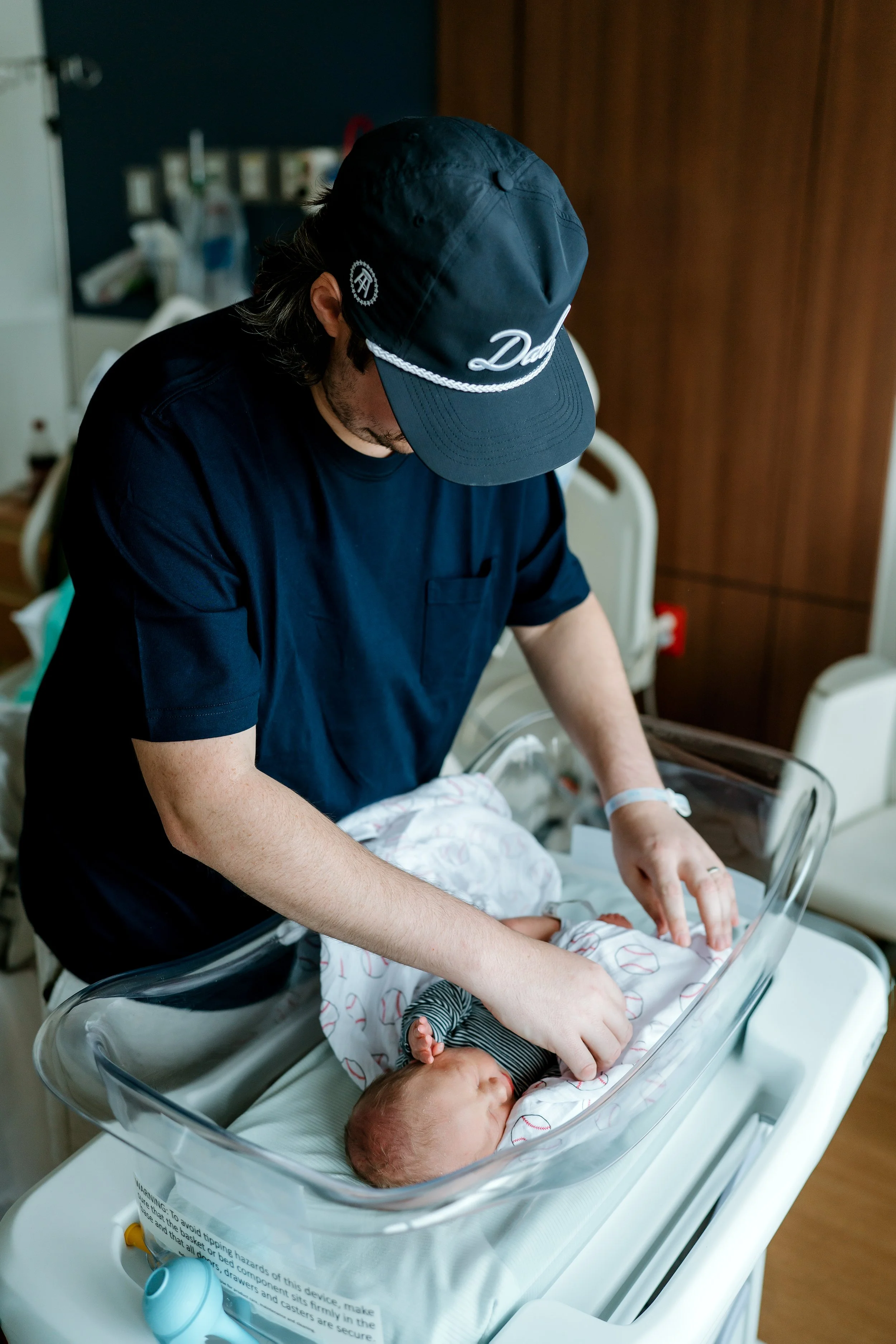 Father gently caring for his newborn baby in the hospital during a Fresh 48 photography session in The Woodlands, TX