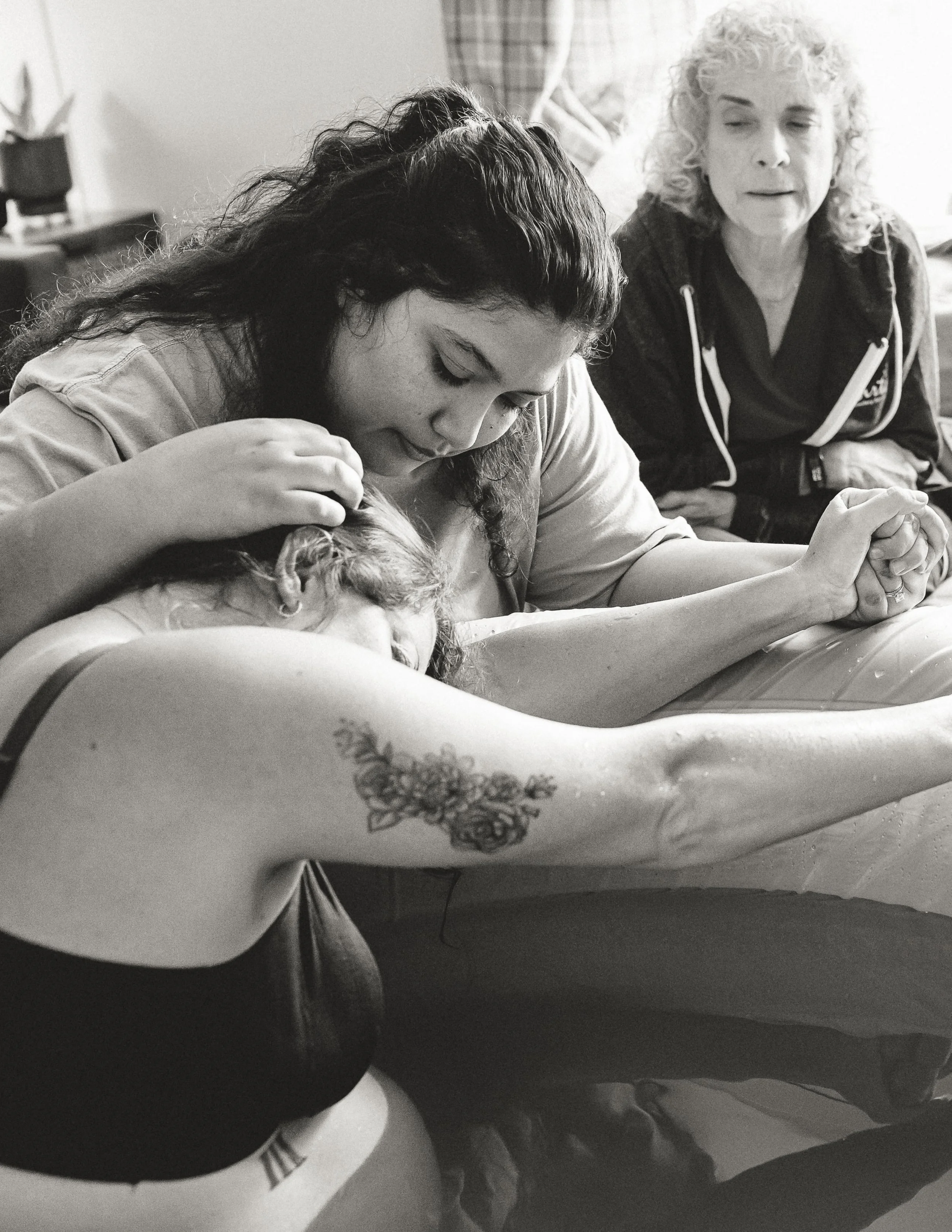 Mother receiving hands-on support during labor in a birth pool during a birth photography session in The Woodlands, TX