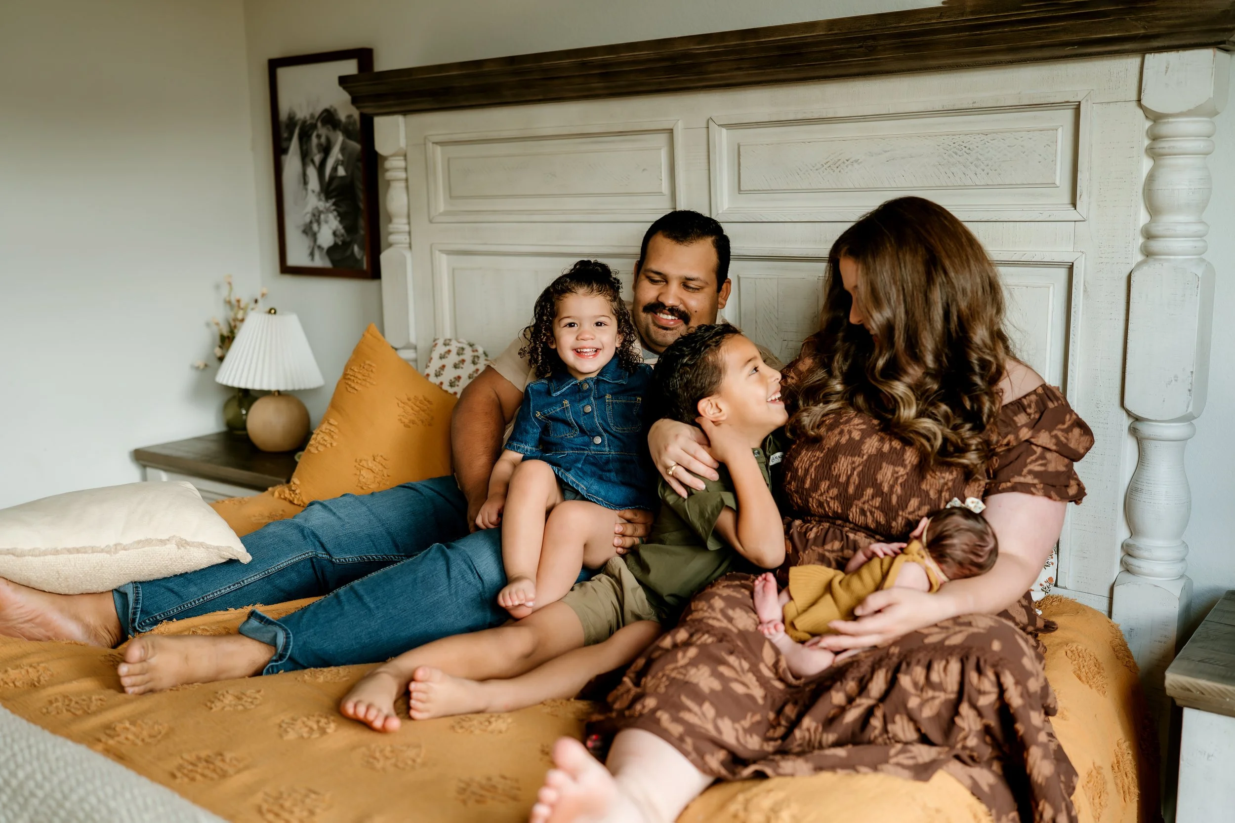 Family of five cuddling together at home during a lifestyle newborn photography session in The Woodlands, TX