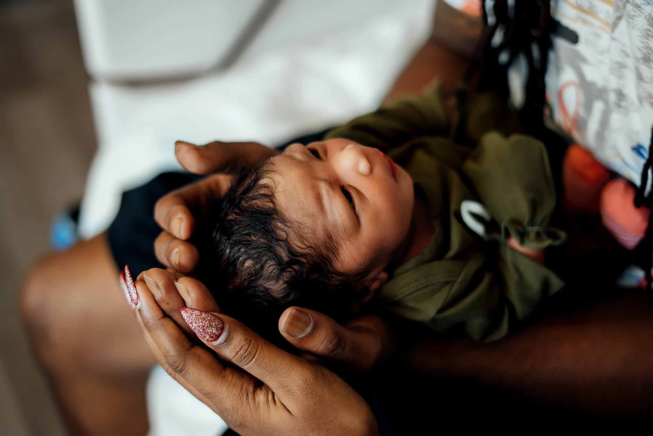 Newborn baby being gently held by parents during a Fresh 48 photography session in The Woodlands, TX