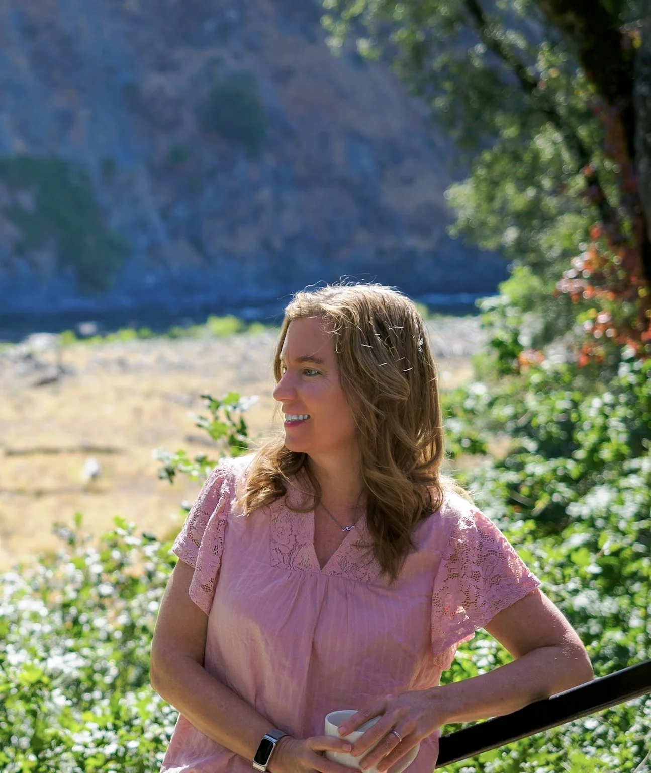 Jen Hult, coach, in a pink top relaxing outdoors with tea