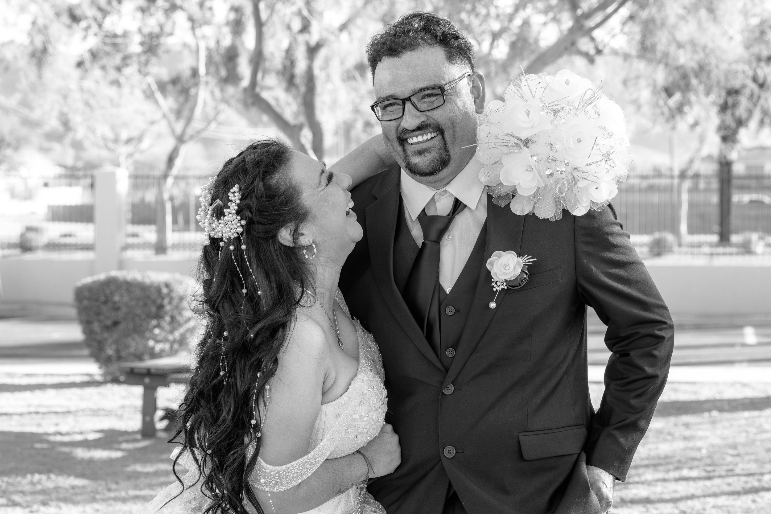 A bride and groom celebrating outdoors, smiling and laughing, with the bride looking up at the groom.