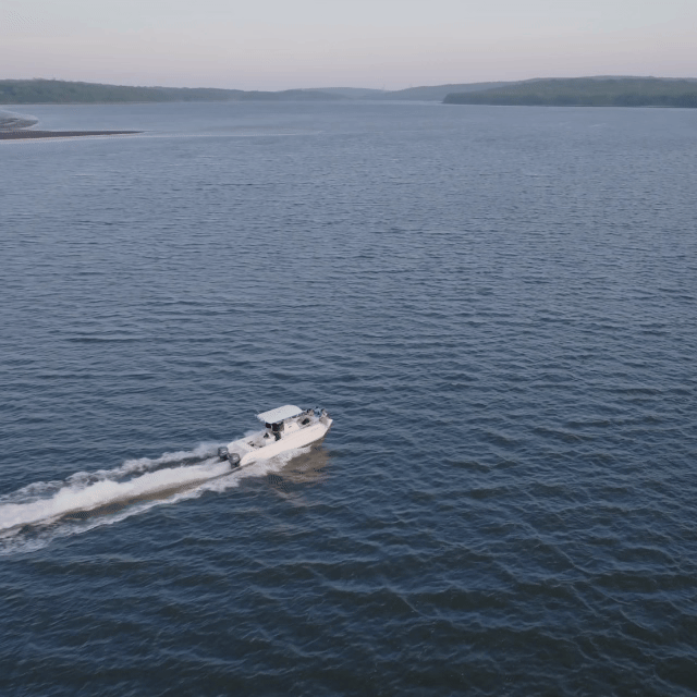 Wedding Videographers in Maine. Wedding Venue in Maine by the water. A white motorboat speeding across a large body of water with land visible in the distance.