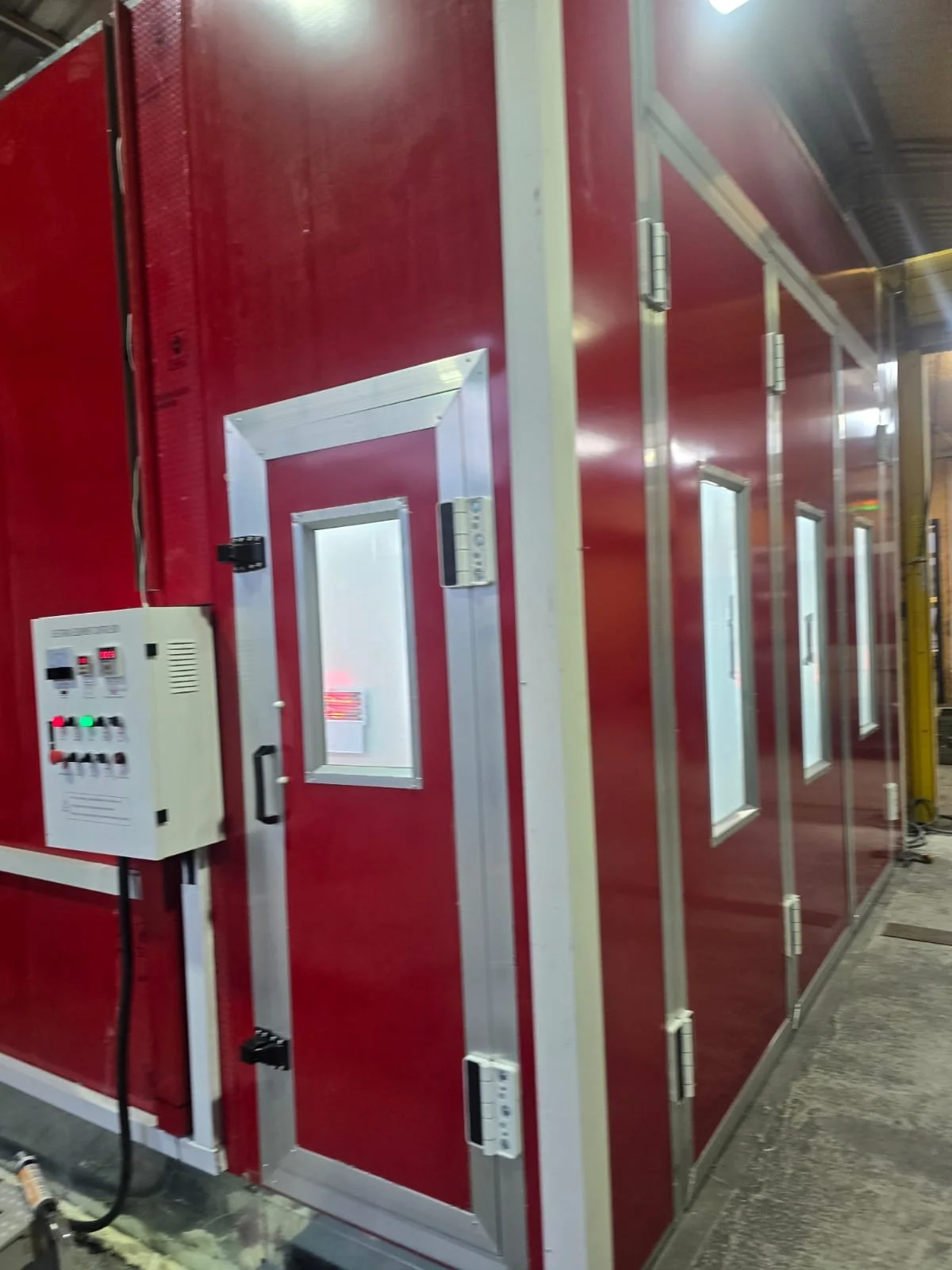 Ein roter Raum mit mehreren Türen und kleinen Fenstern in einer industriellen Umgebung.