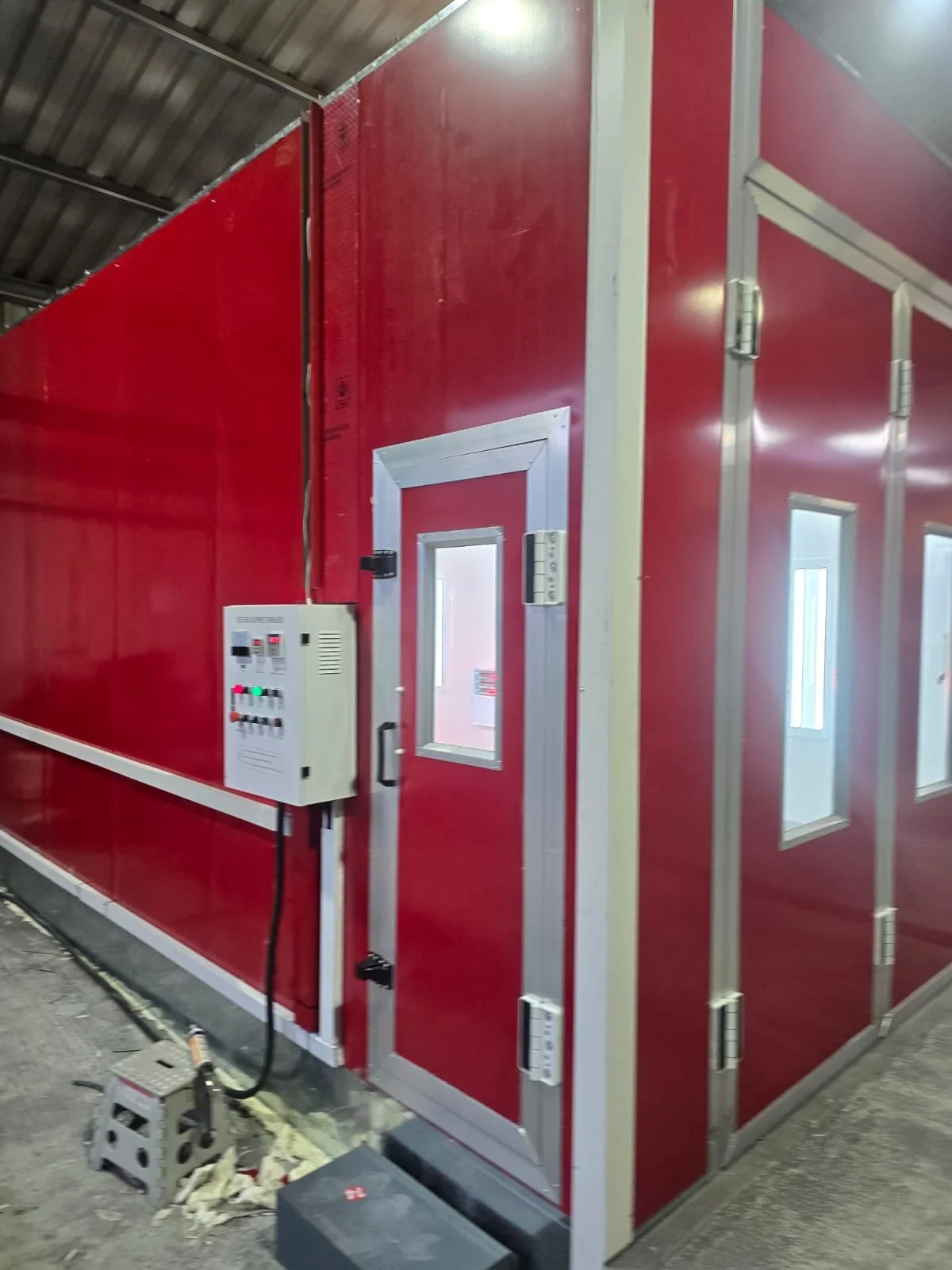 Ein rotes Isolationsraum mit einer Tür und kleinen Fenstern, technischer Ausstattung und Kabel auf dem Boden.