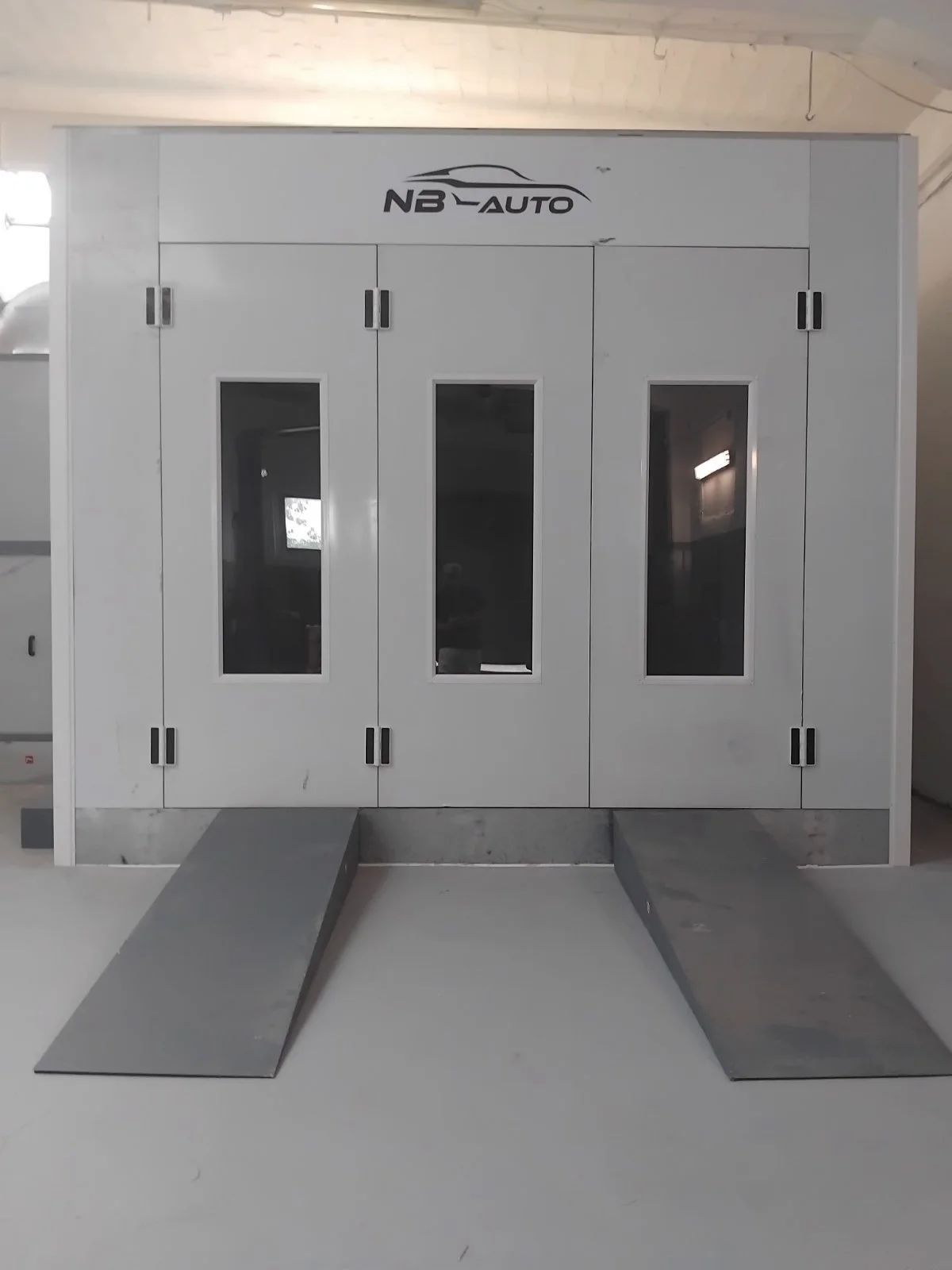 Ein graues Fahrzeugservice-Schrank mit zwei Rampen davor und einem Logo 'NB-Auto' oben