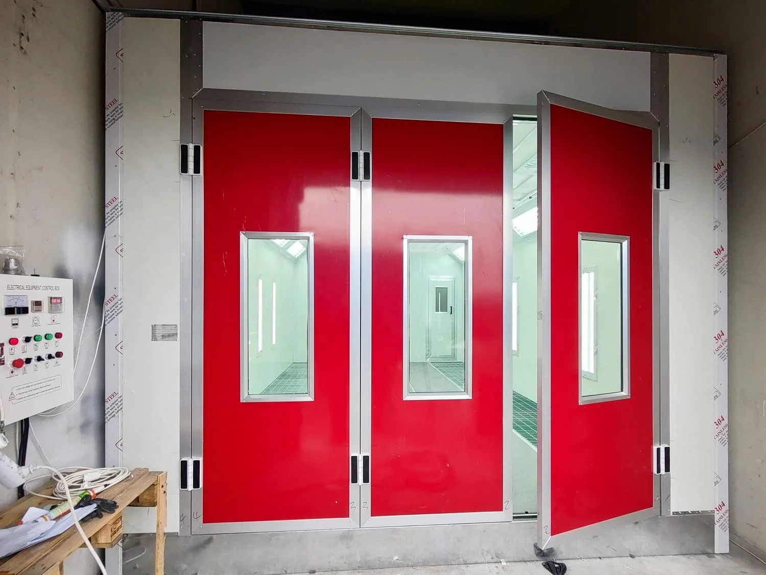 Rote Brandschutztüren mit kleinen Fenster in einem Gebäudeteil, wahrscheinlich eine Feuerwache oder ein ähnlicher sicherheitsrelevanter Bereich.