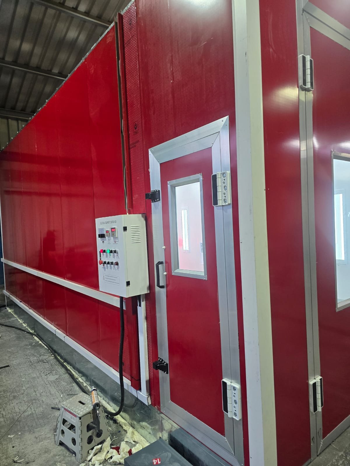 Ein rotes Isolationszelt mit einer Tür und Fenstern, wahrscheinlich für Test-, Forschungs- oder Hygienebedürfnisse, mit elektronischer Steuerung an der Außenseite.