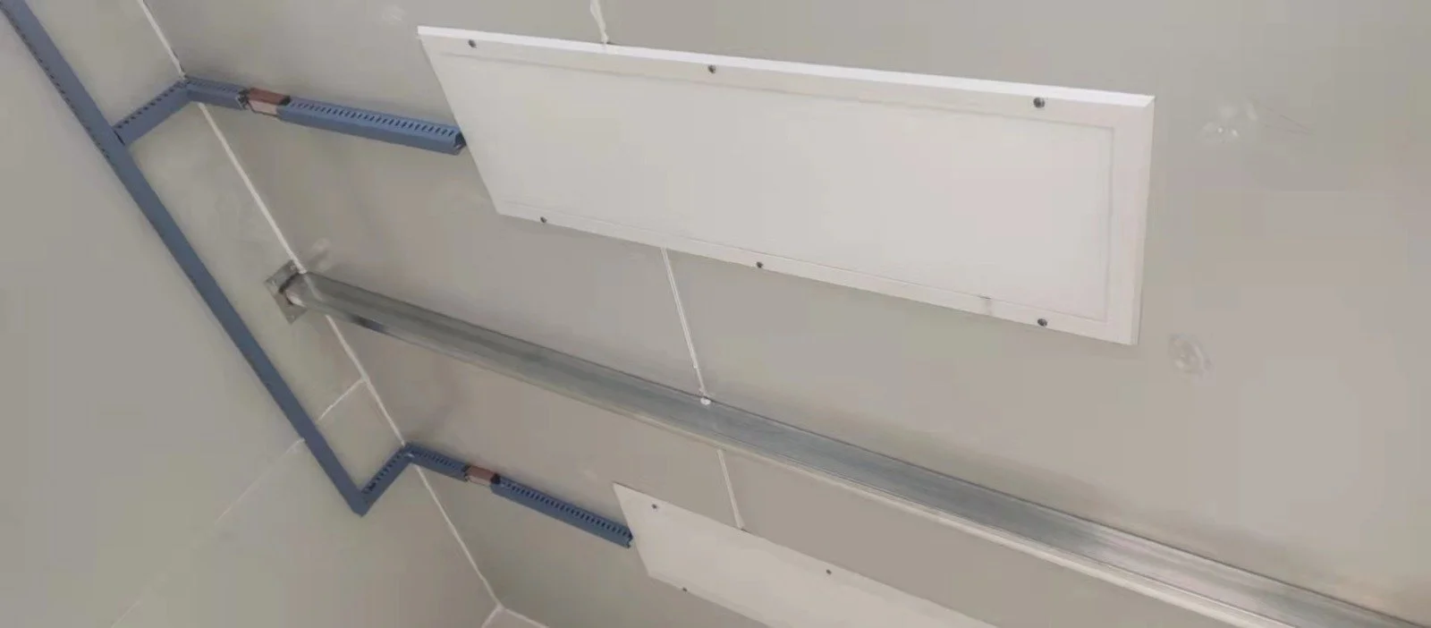 Blick nach oben auf eine Wand mit Kabelkanälen und dafür vorgesehenen Ausbauöffnungen, die für elektrische Installationen vorbereitet sind.