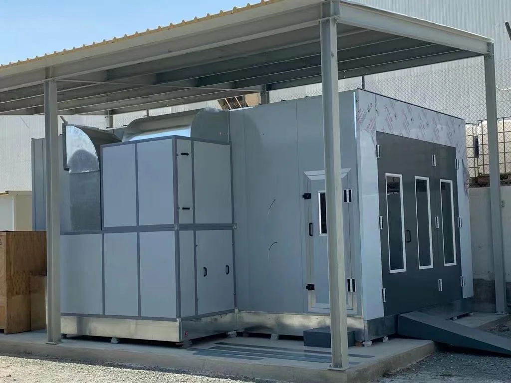 Ein modulartes Gebäude mit mehreren Türen und Fenstern, auf einer betonierten Plattform unter einem Metalldach, im Freien.