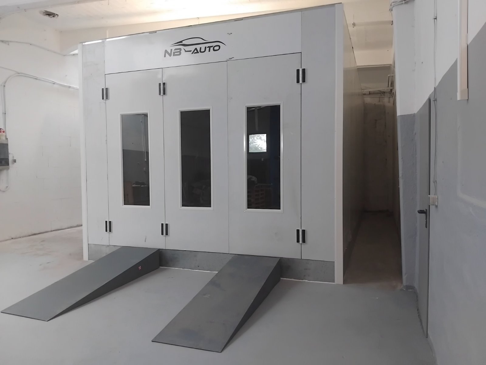 Ein mobiler Fahrradbox mit Rampe, weiß mit Fenster, in einer Garage