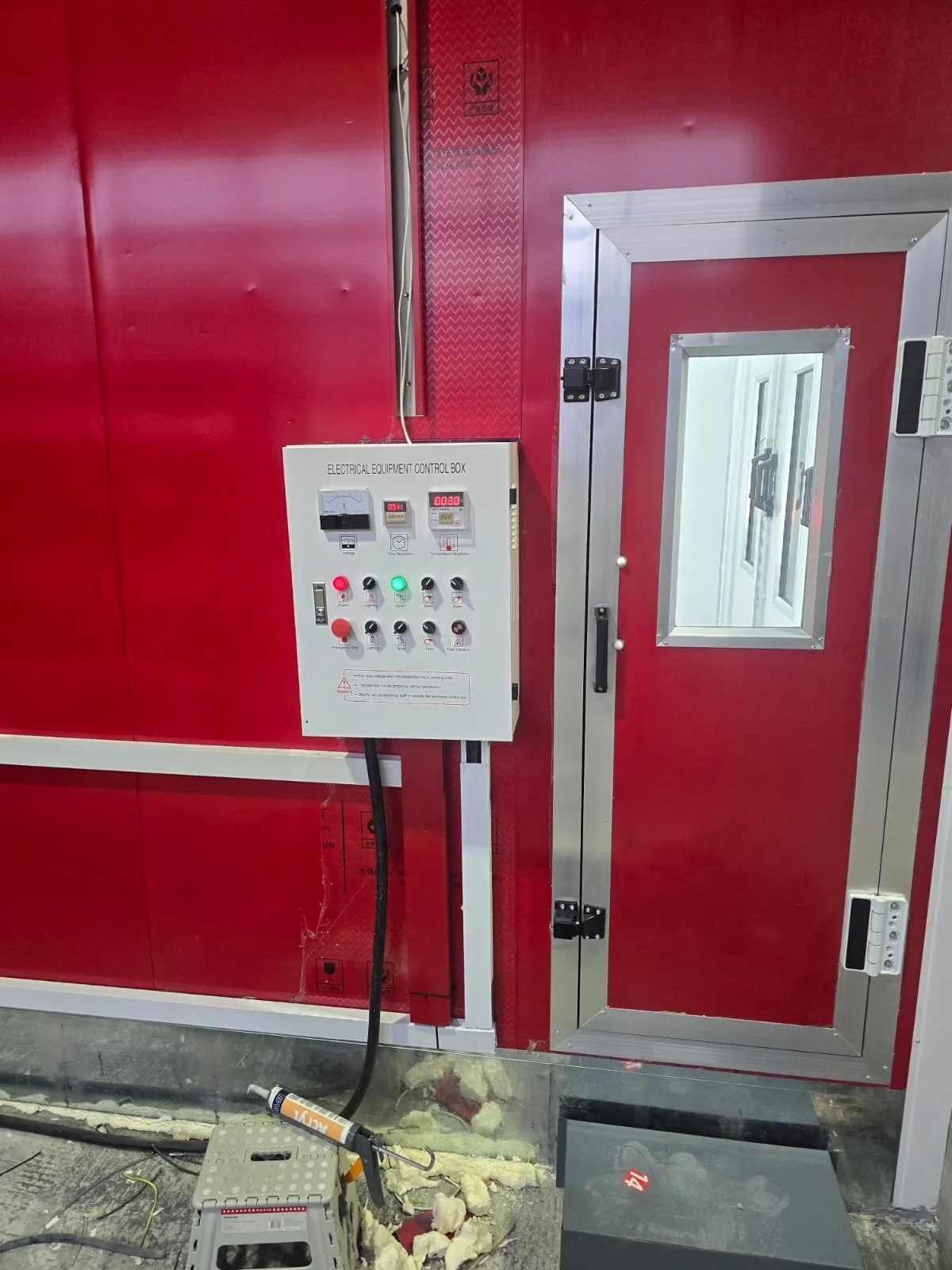 Elektrischer Geräte-Steuereinheit an einer roten Wand mit einer Tür mit einem Fenster