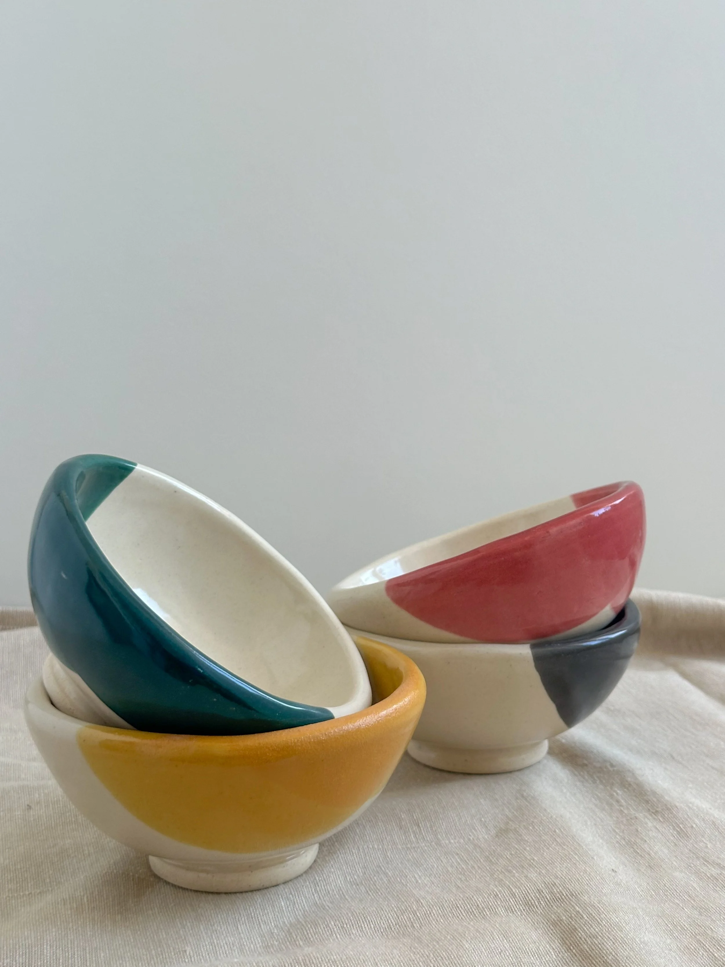 Stacked ceramic bowls with colorful accents on a neutral tablecloth.