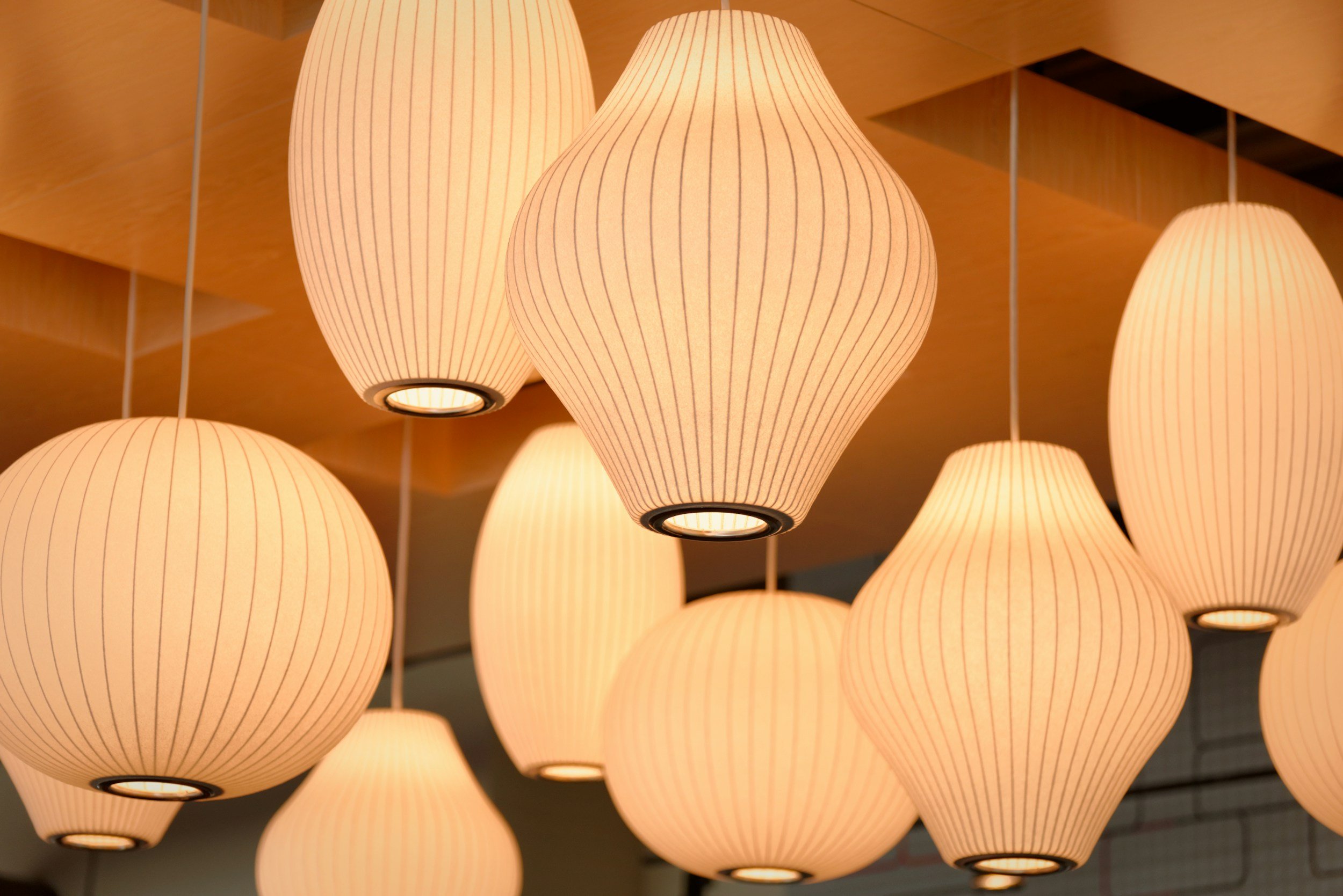 Multiple hanging paper lanterns with a warm glow in a modern interior ceiling.