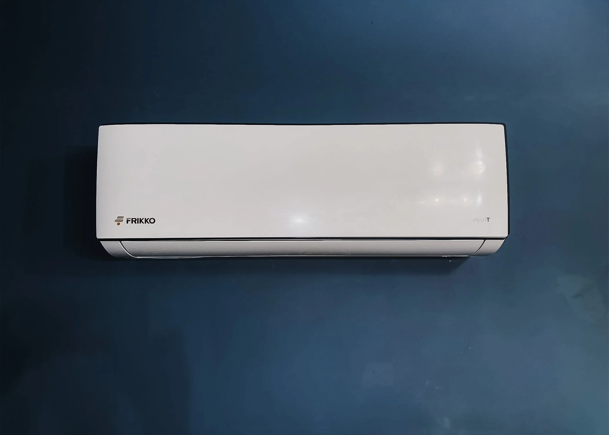 White wall-mounted air conditioning unit on a dark blue wall.