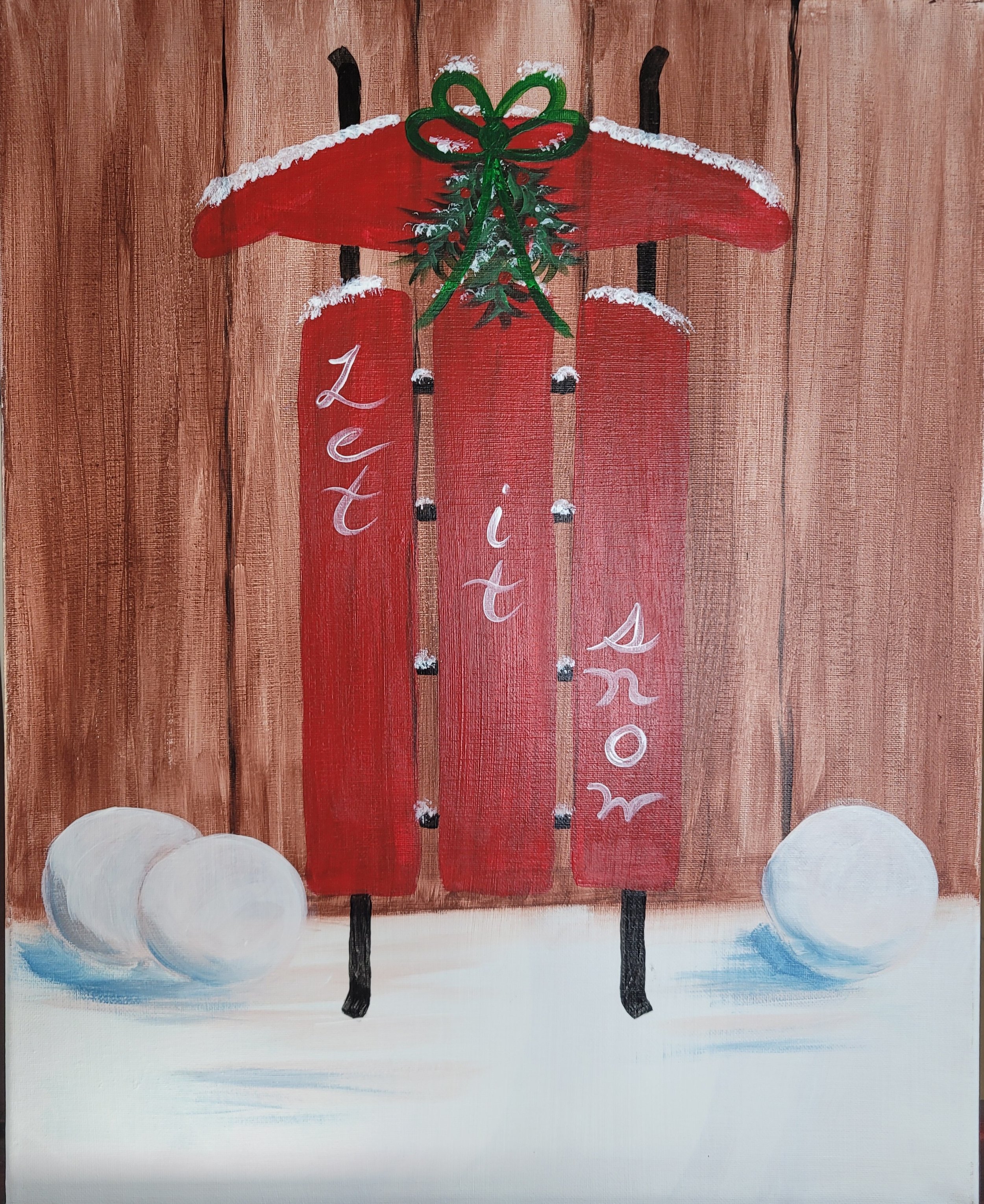 Painting of a red sled with "Let it snow" written on it. The sled is adorned with a green bow and greenery at the top. There are snowballs and snow at the base of a wooden fence background. Paint party acrylic painting.