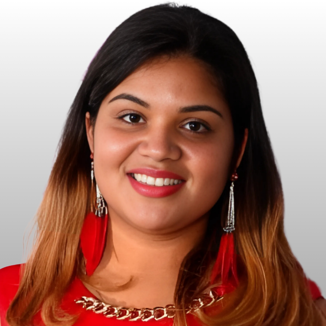 Person wearing red earrings and a red outfit with a chain detail, smiling against a light background.