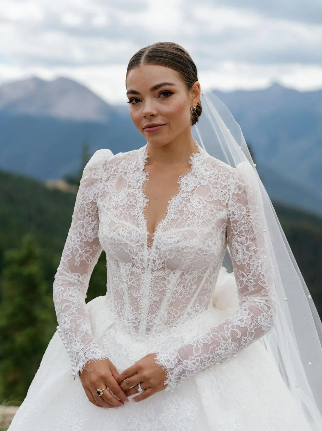 Bride in a lace wedding dress with mountains in the background.