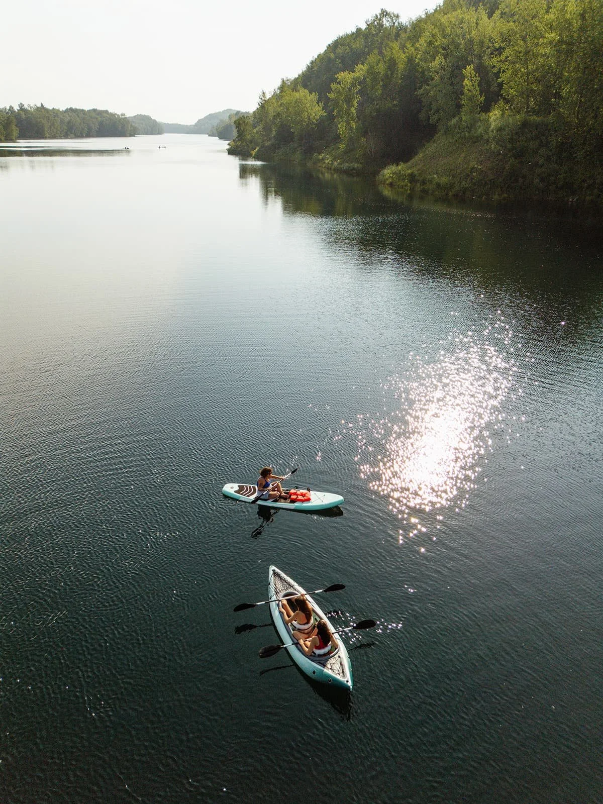 Lush green trees reflected in a calm, blue lake under a clear sky.