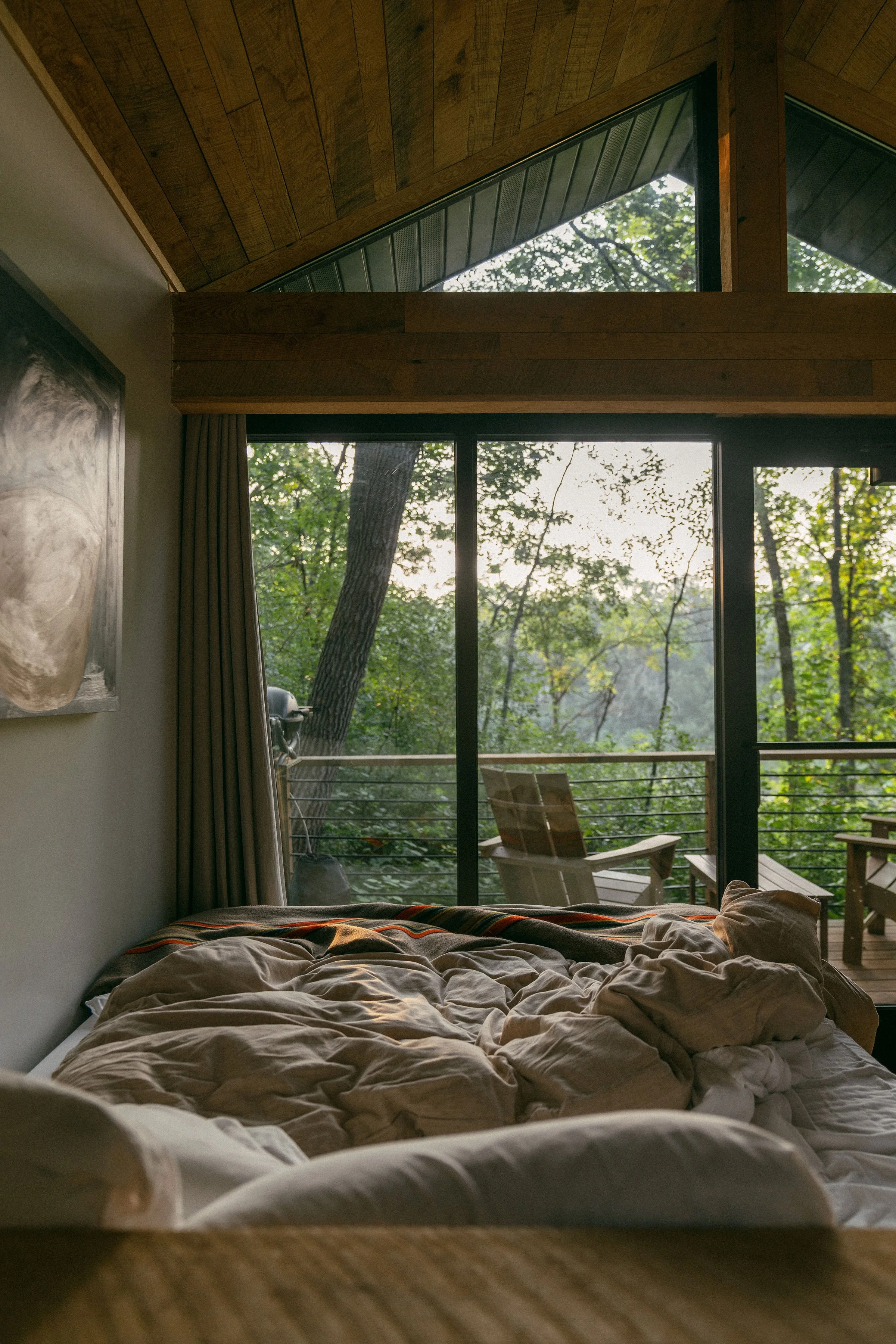 Luxury modern cabin bedroom with large windows overlooking the forest