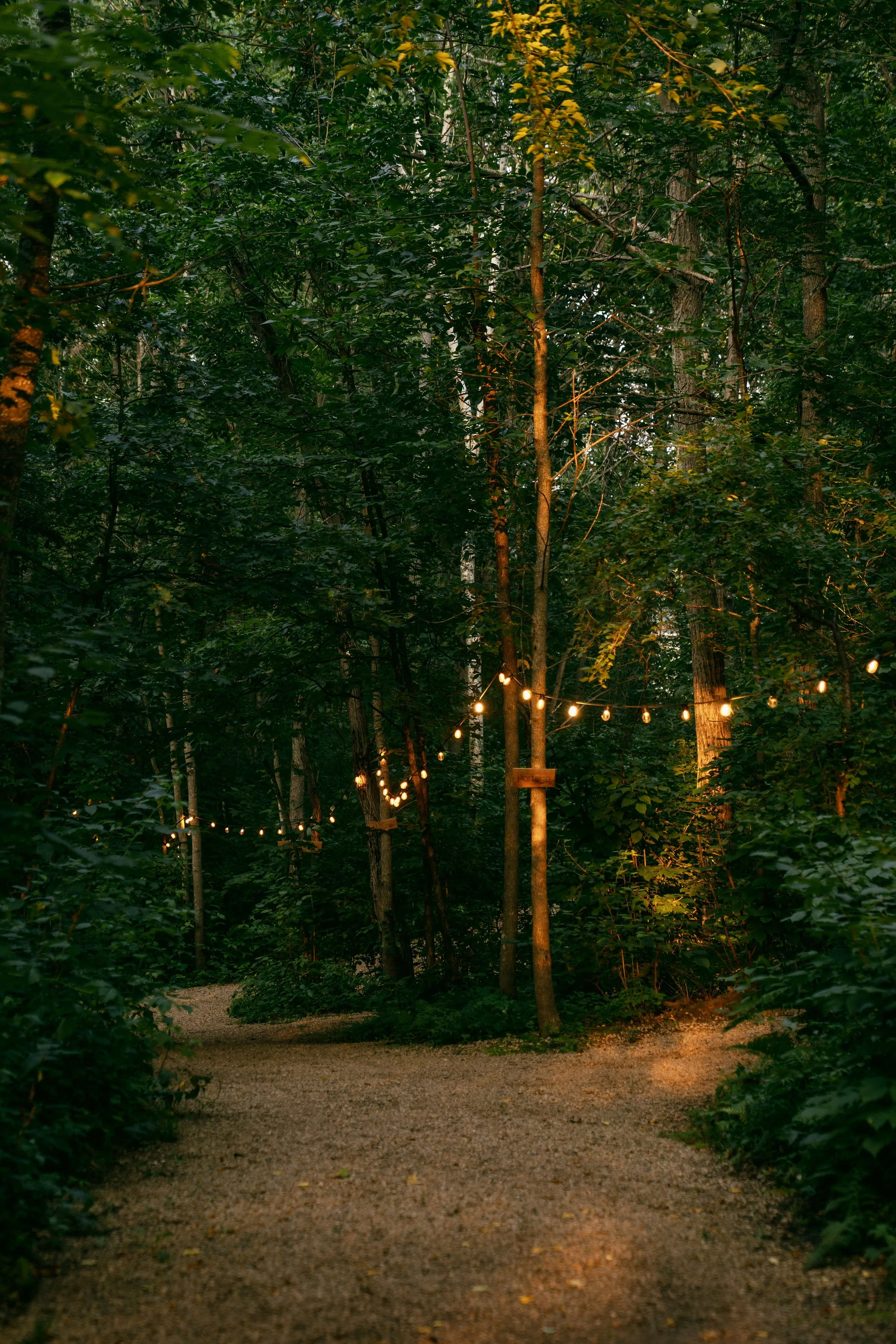 Wooden bed with pillows and a striped blanket, hiking boots on floor, wooden chair outside glass door, cozy interior.