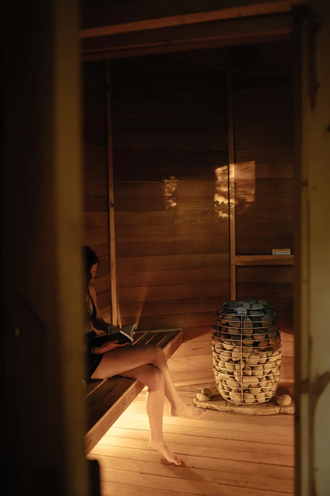 Guest relaxing in the redwood sauna at Cuyuna Cove with a HUUM stove and infrared, a calming way to relax muscles and recover after a day outdoors in Crosby Minnesota
