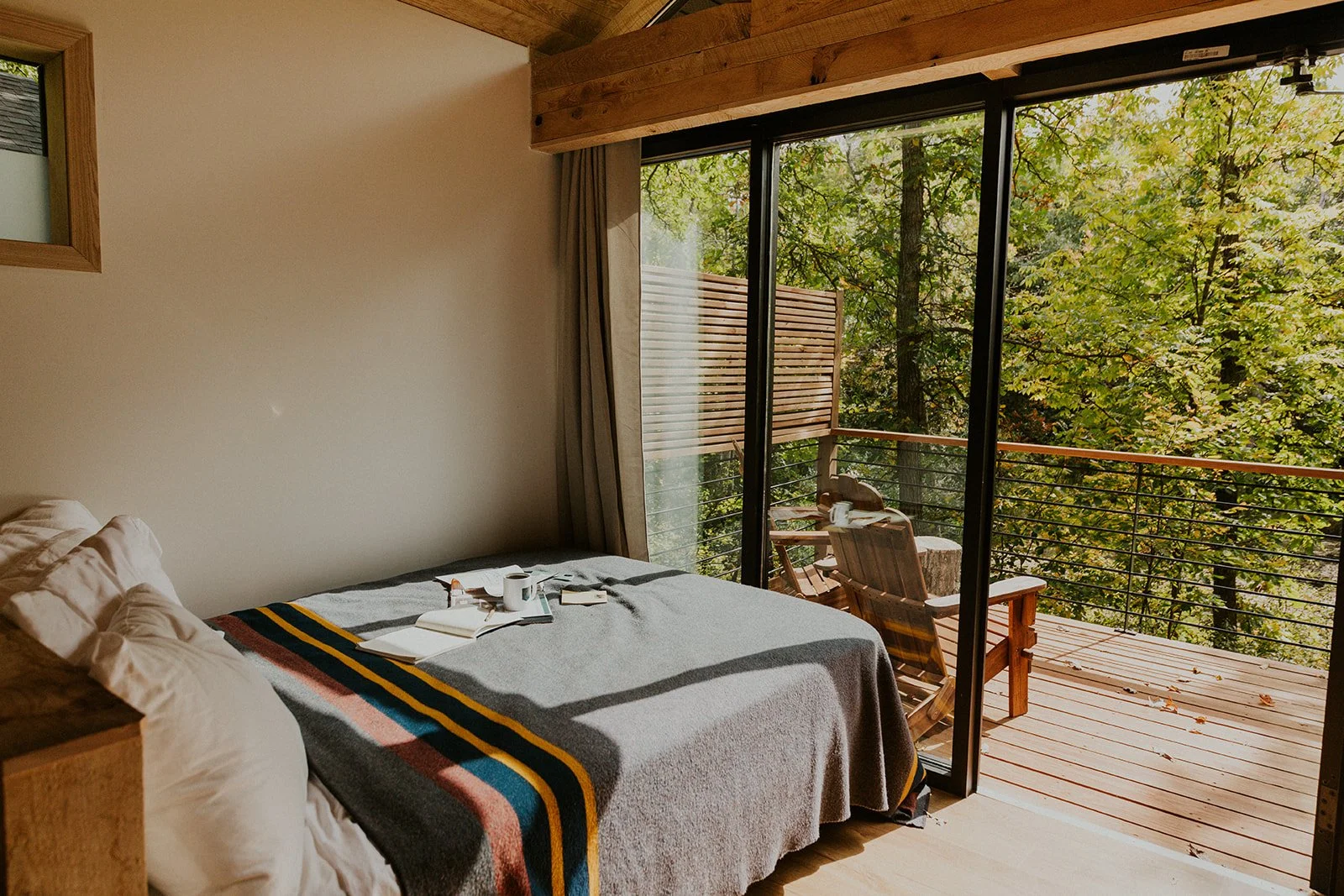 Modern cabin with large windows surrounded by lush green trees