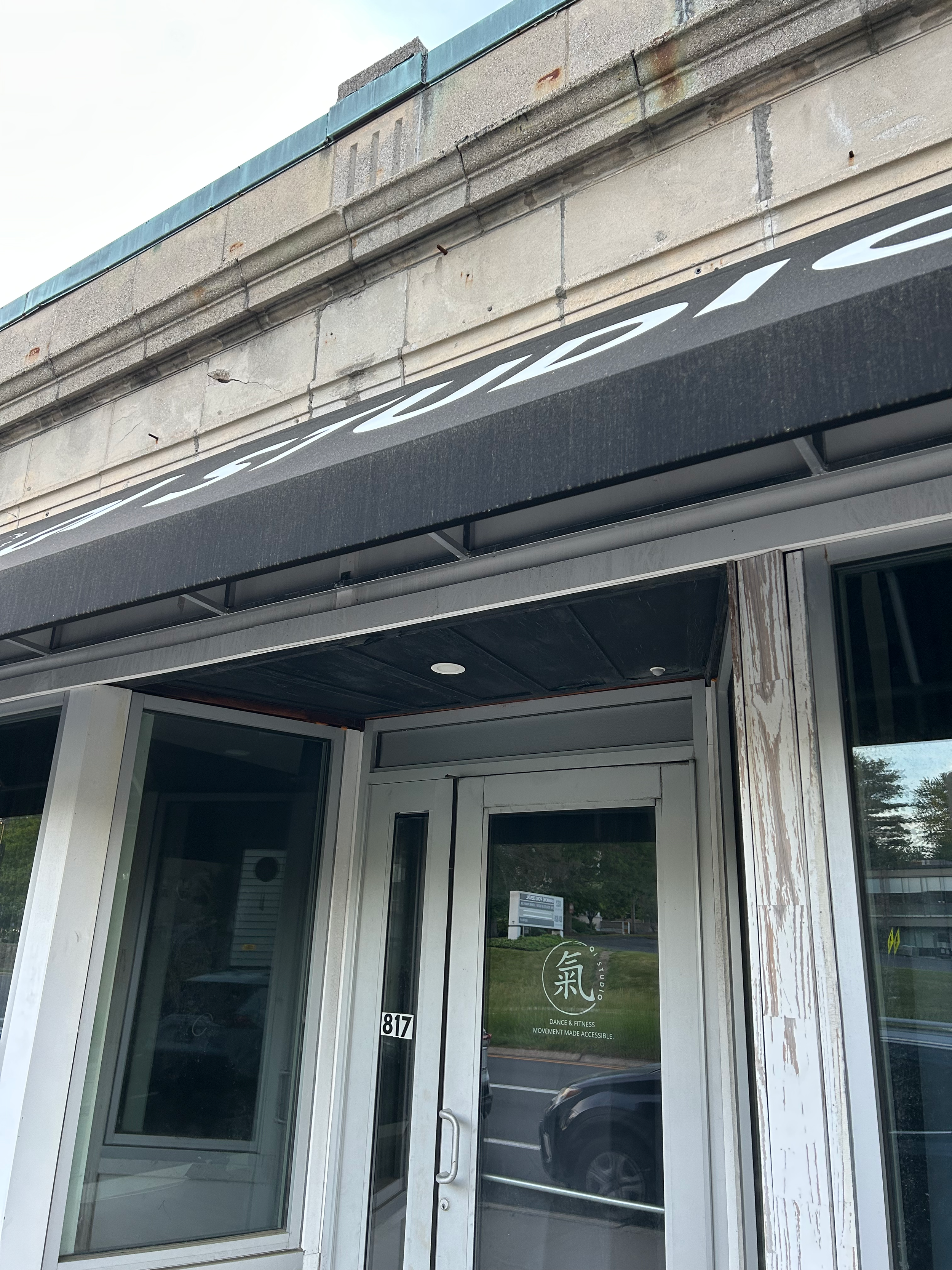 white store front with black awning reading qi studio dance and fitness