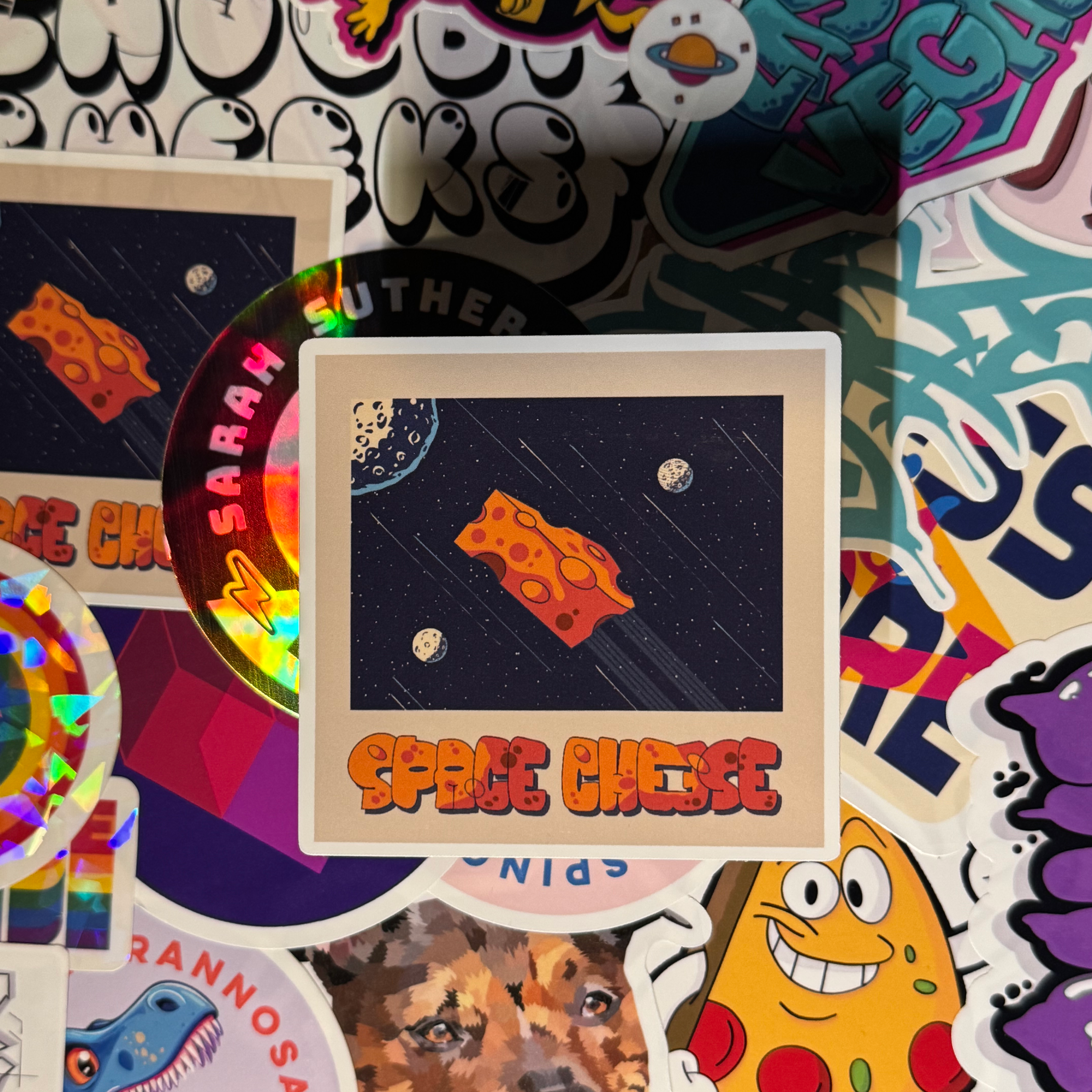 photo of hand-made sticker to show size and quality of a space scene with a chunk of cheese shooting through the middle like a rocket with the text space cheese written below in graffiti