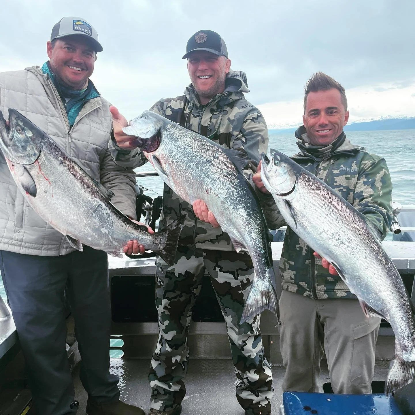 Anglers holding freshly caught salmon aboard a fishing charter in Kachemak Bay near Homer, Alaska, during a guided saltwater fishing tour on the Kenai Peninsula.