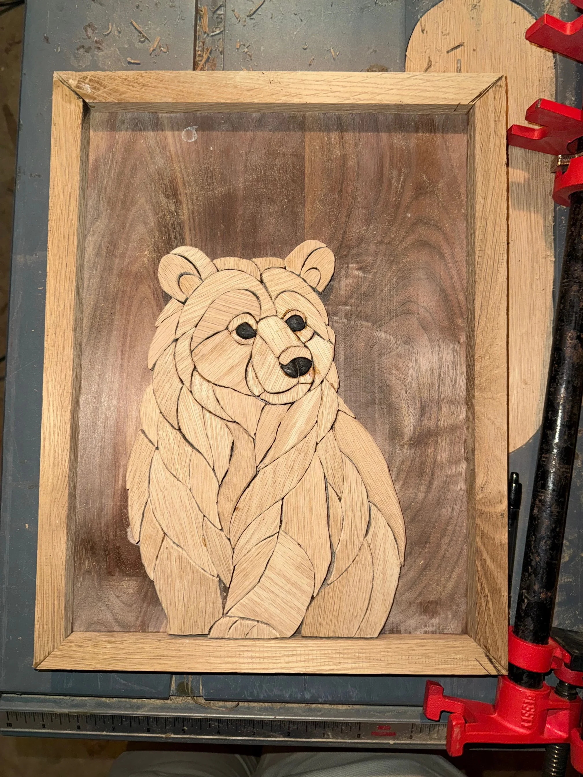 Wooden wall art of a bear created with layered wood pieces, framed in a wooden border.