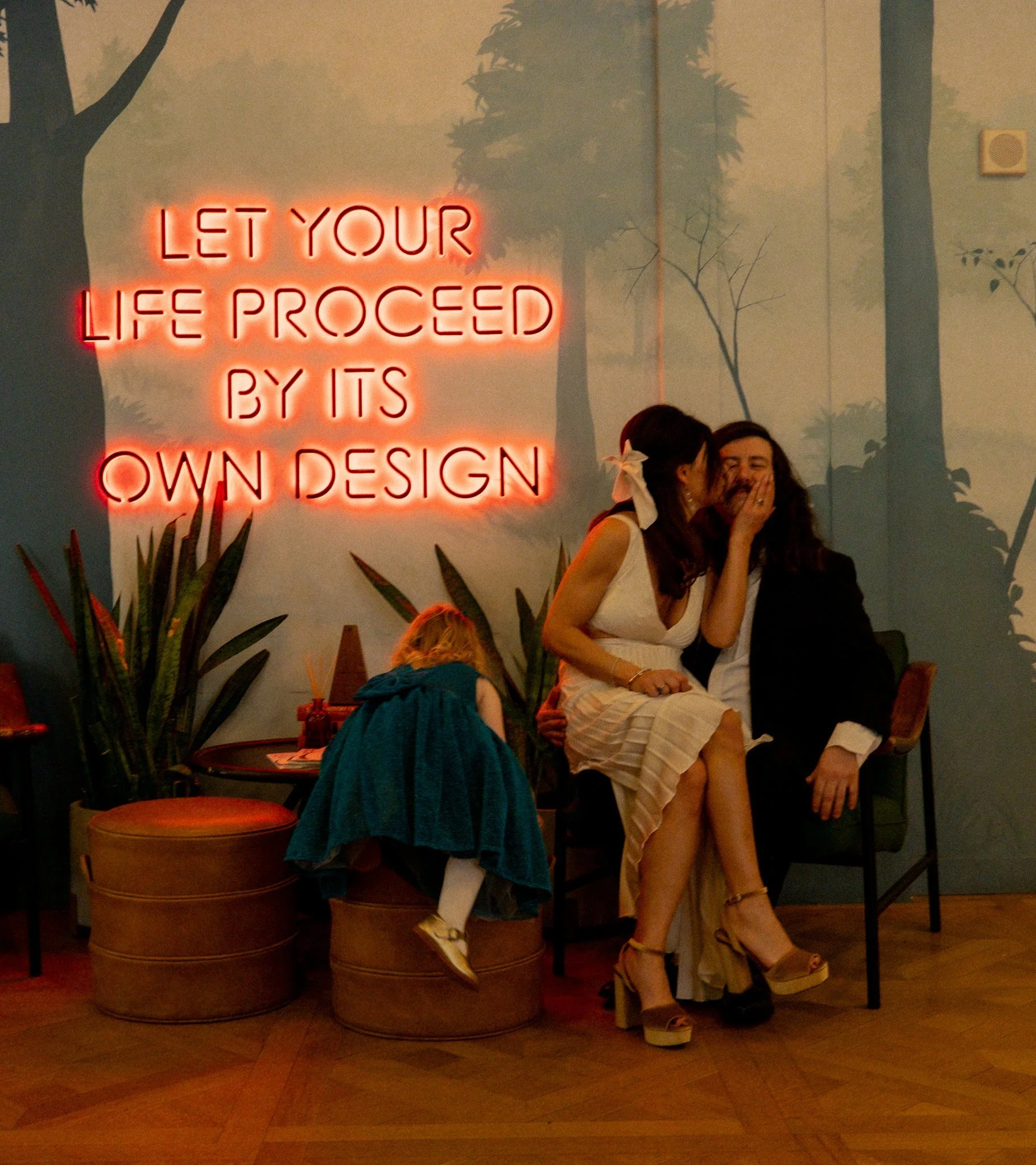 couple sitting on chair with neon sign