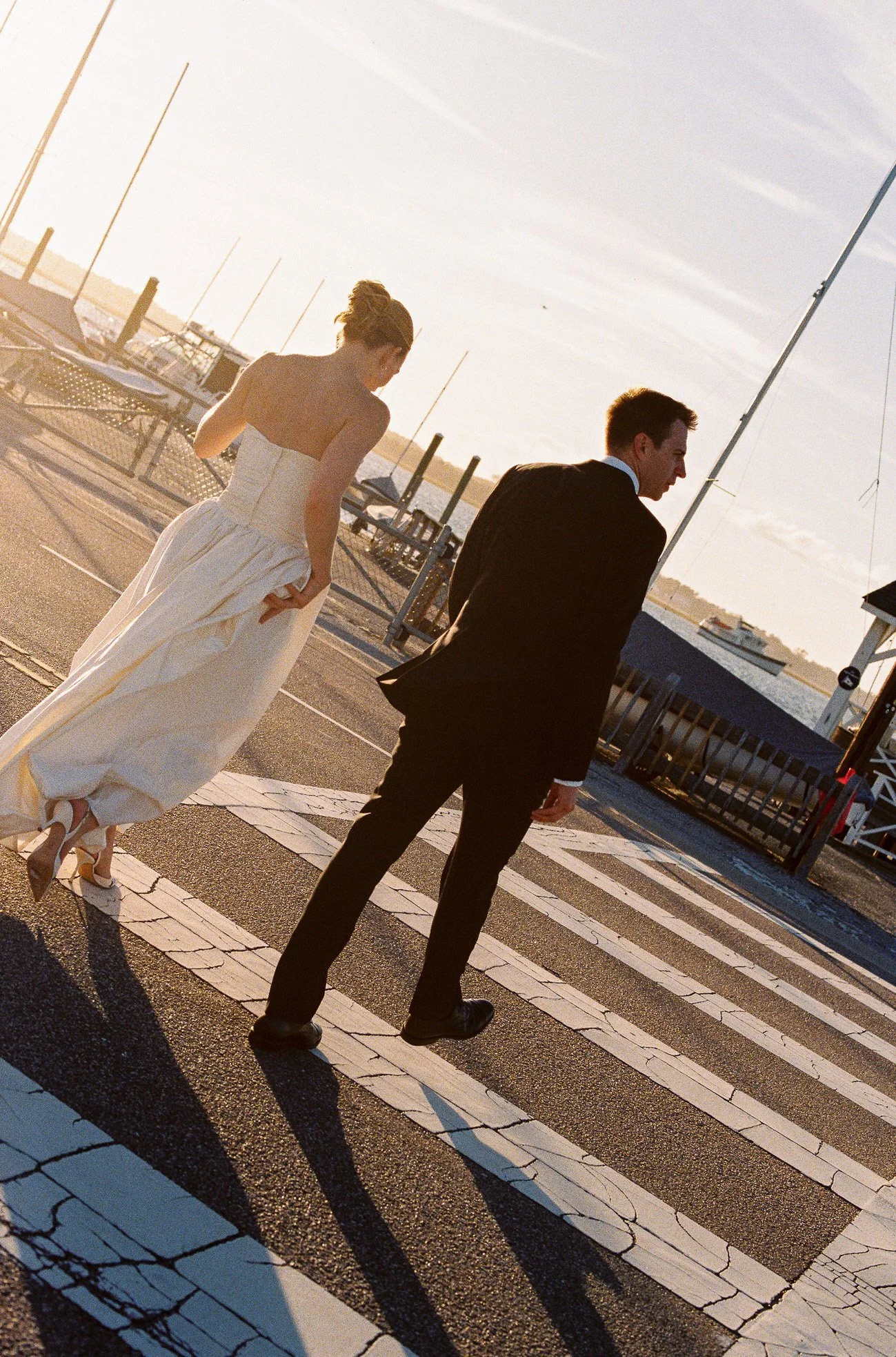 sunlit portrait of bride and groom crossing the street