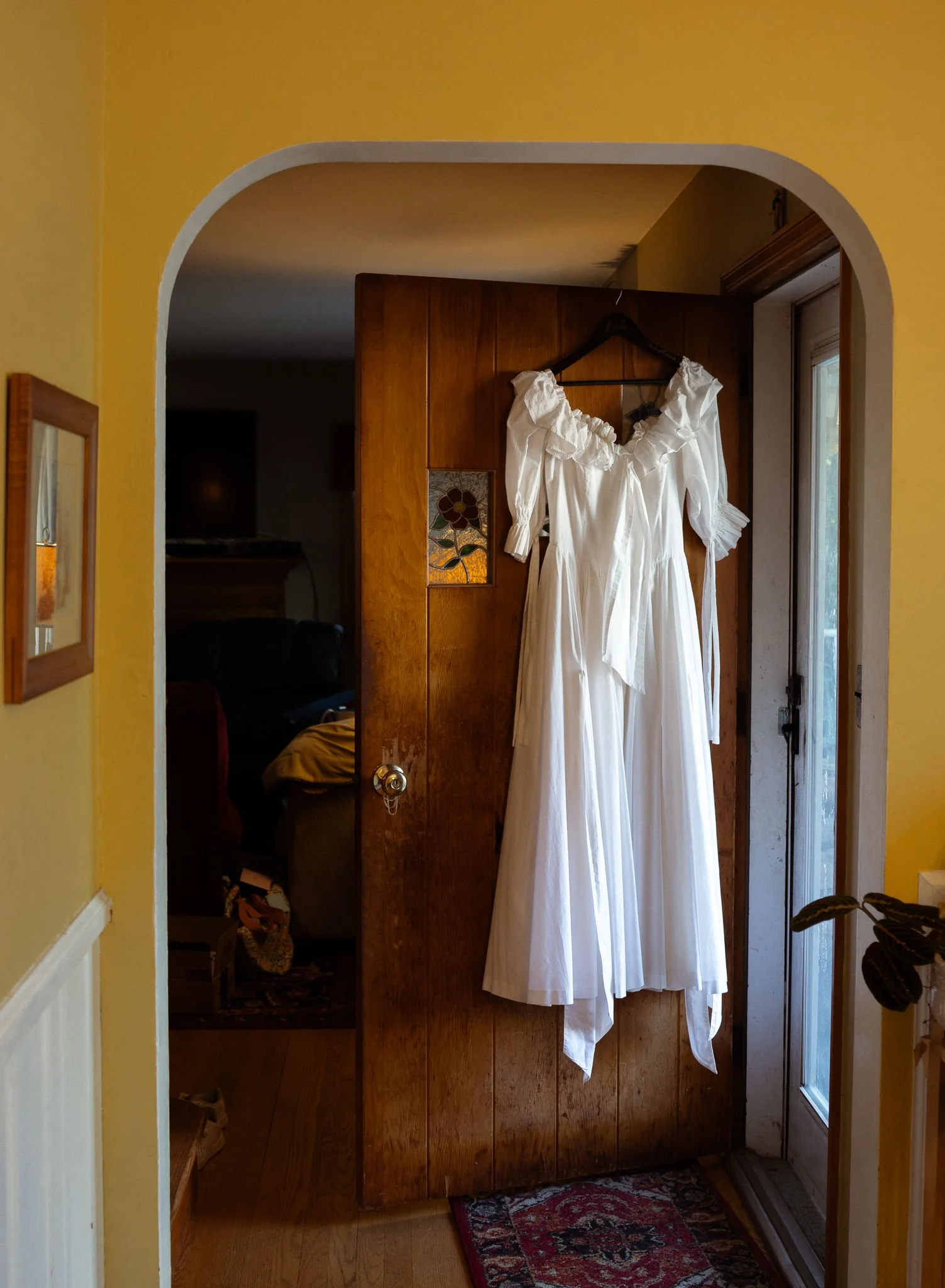 wedding gown hanging with yellow walls