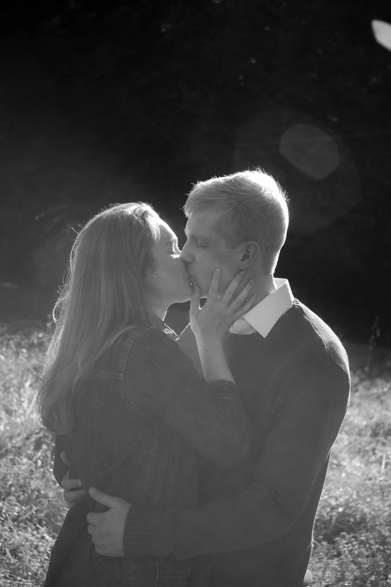 black and white portrait couple kissing in field