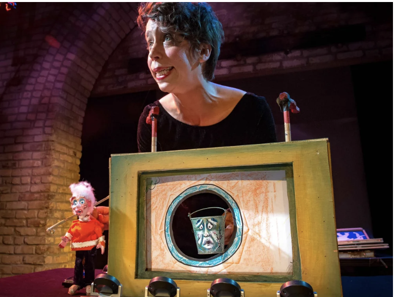 Two performers, one in the foreground wearing a moon shaped hat and the other in the background wearing a star shaped hat
