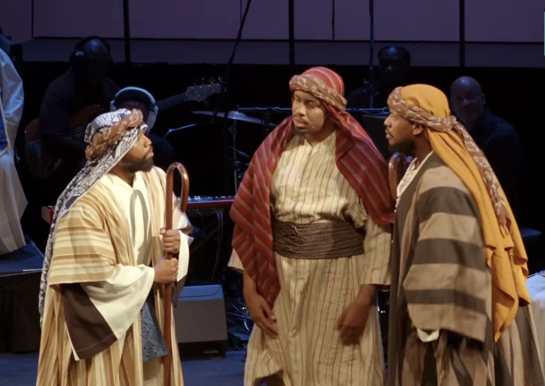 Three men in biblical costumes performing on stage.
